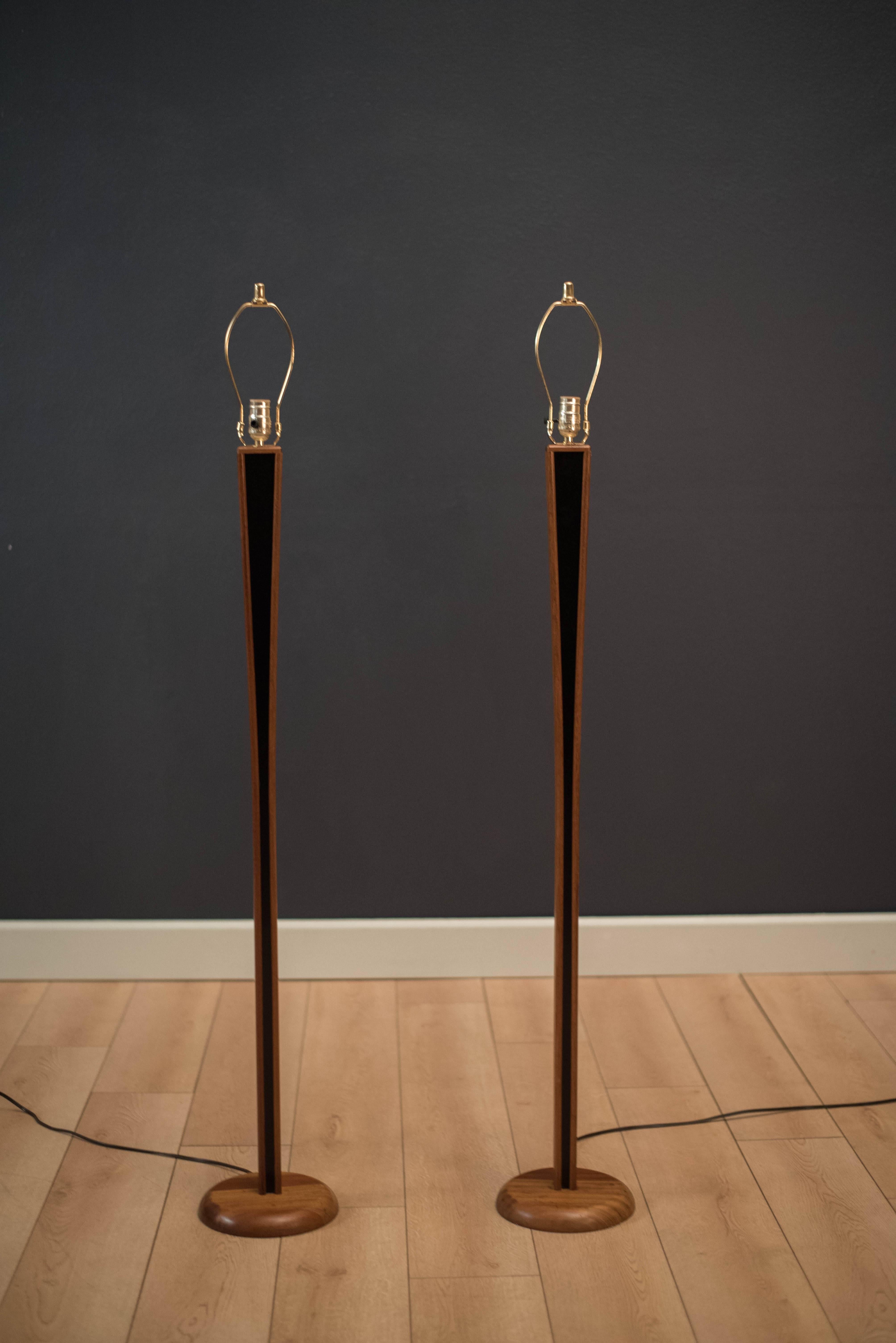 Vintage pair of teak floor lamps, circa 1970s. This set displays a tapered teak base with a black inset design. Lamps include a three way switch and have been professional rewired. Price is for the pair. 

 