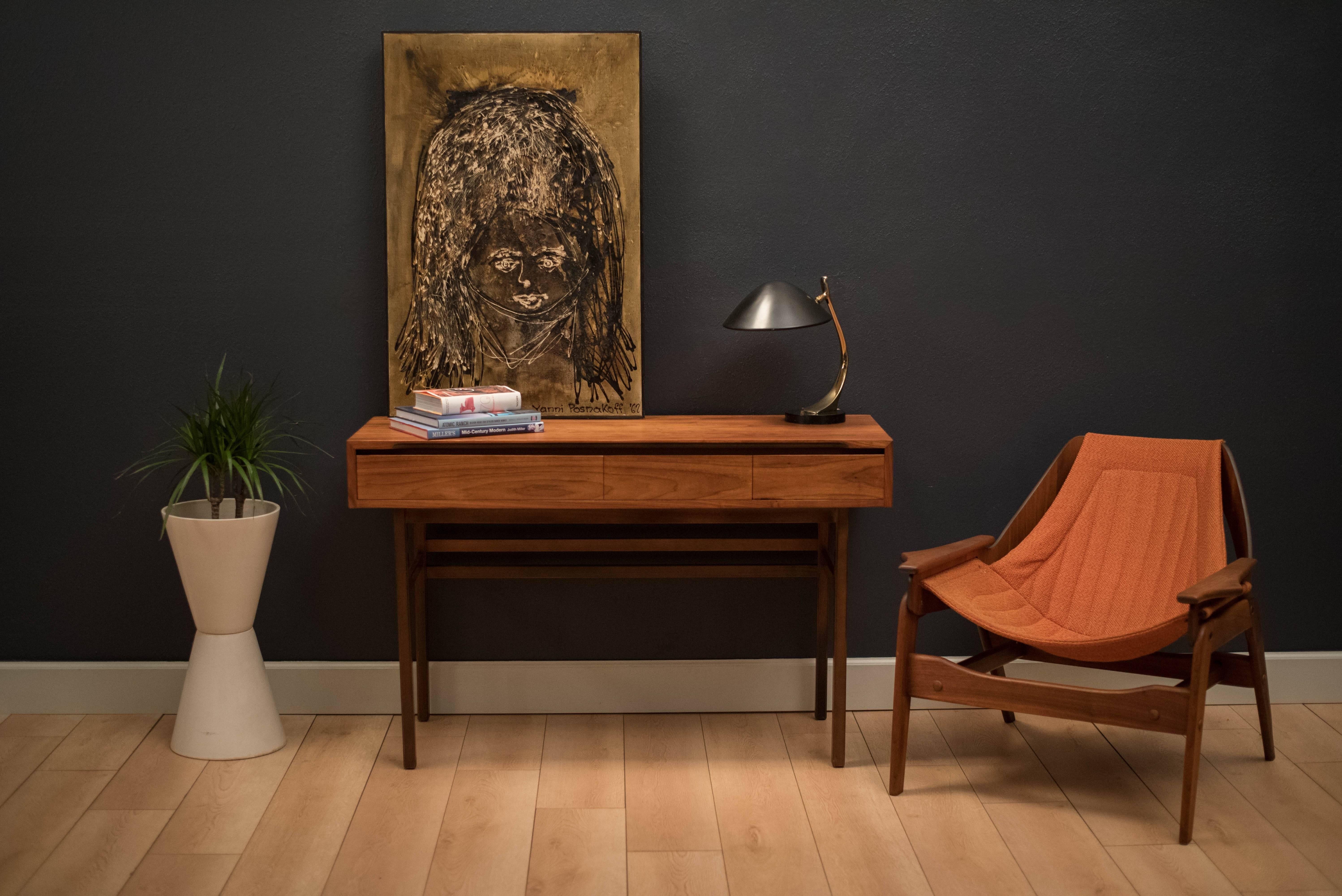 Mid-century walnut console table designed by Kipp Stewart and Stewart MacDougall for Glenn of California, circa 1960s. This versatile piece has three drawers and can also function as a desk.