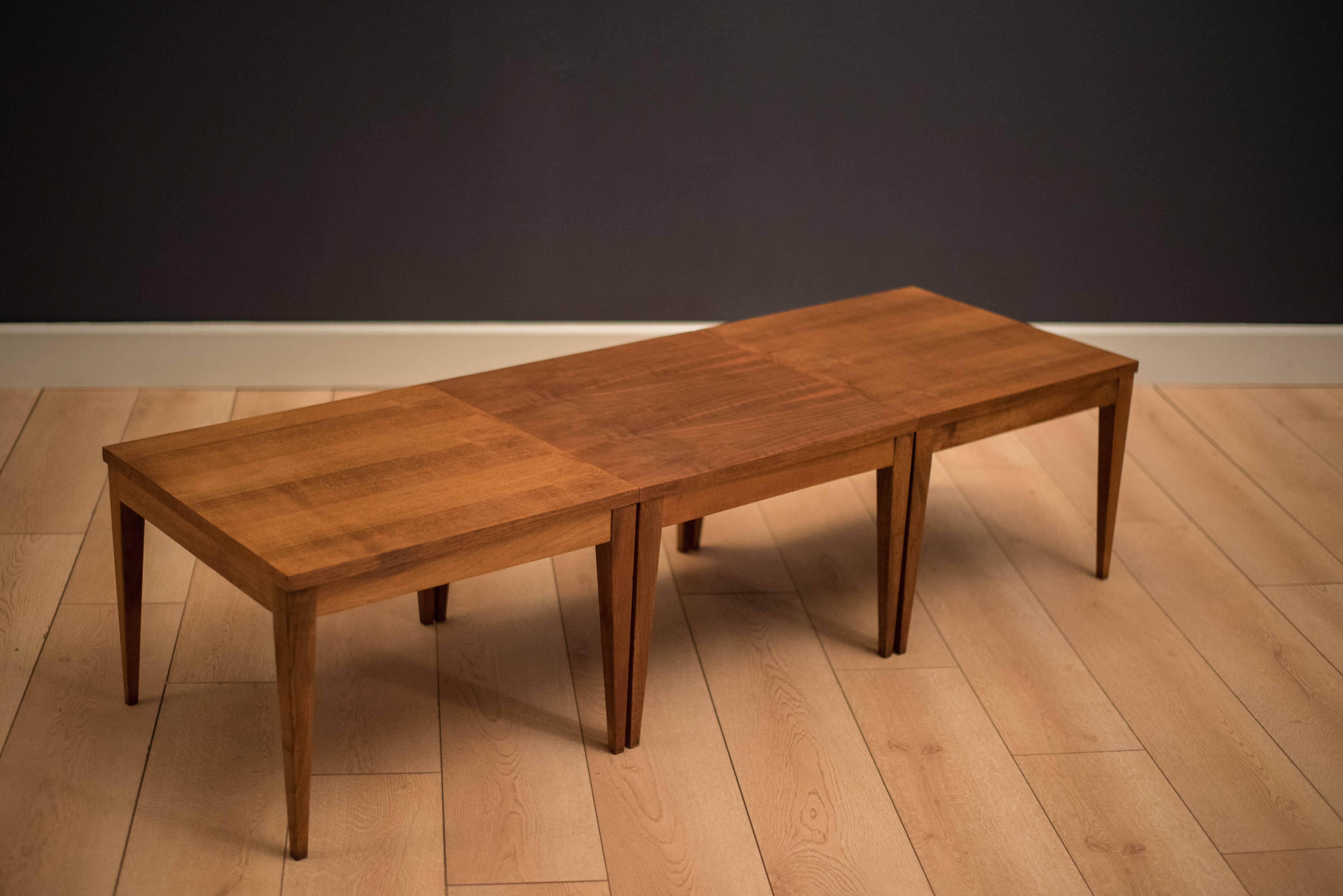 Mid Century set of three matching side tables in walnut with tapered legs. This versatile set can be used together to make a coffee table or separately as end tables.