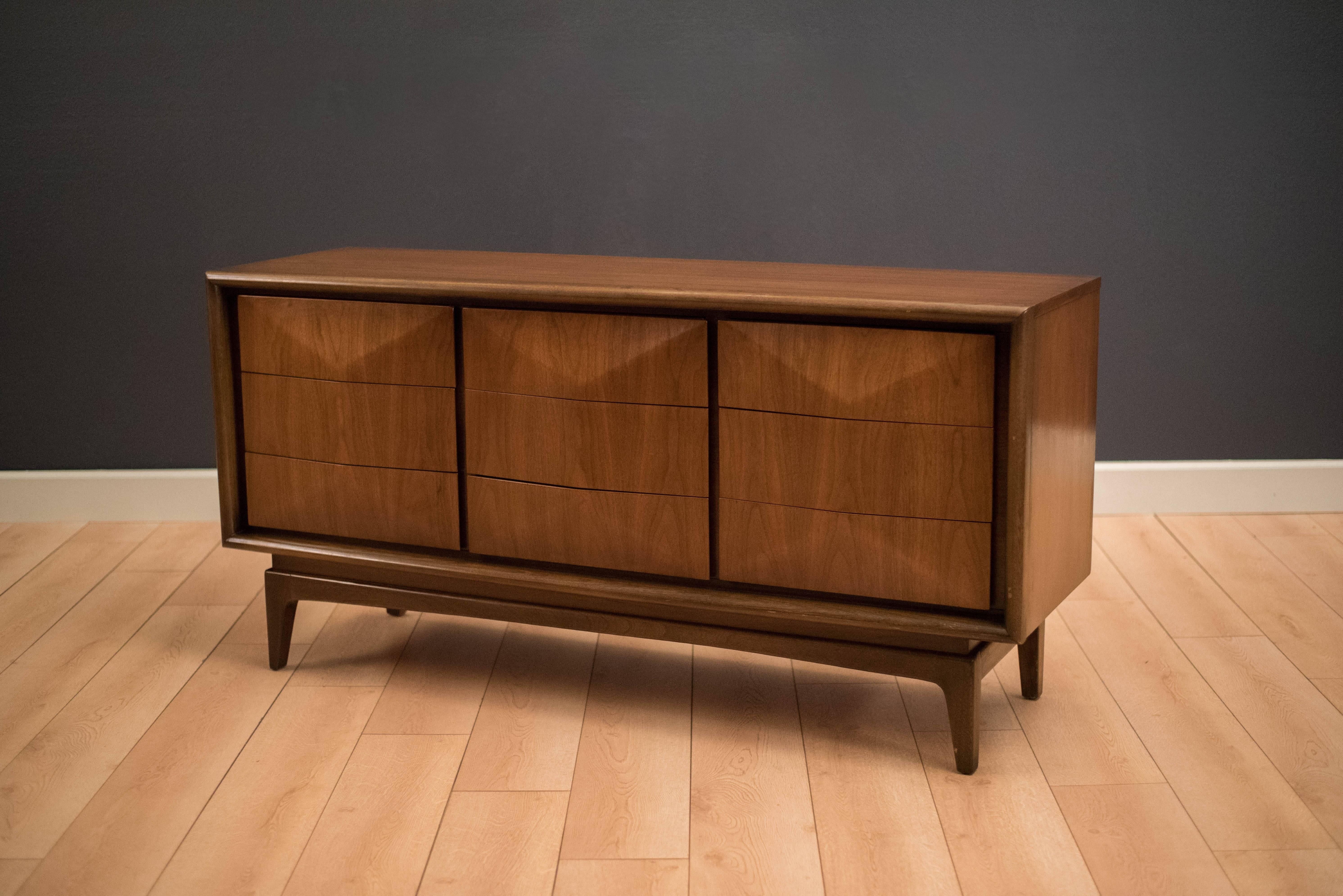 Vintage triple dresser manufactured by United Furniture in walnut, circa 1960s. This piece features nine diamond front drawers that offer plenty of storage space.