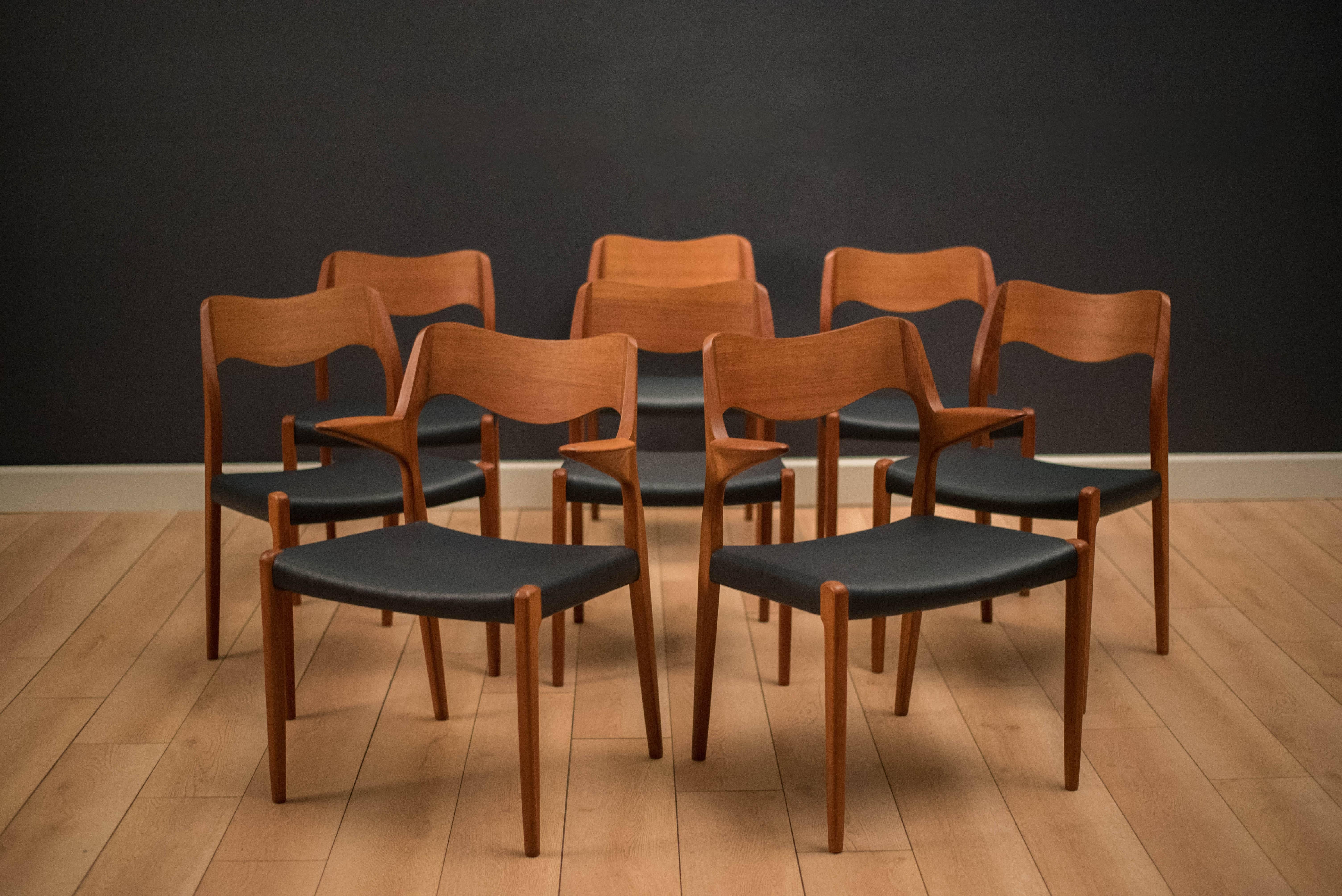 Mid century set of eight Danish dining chairs by Niels Møller for J.L. Møller Møbelfabrik in teak. This set includes six model 71 side chairs and two 55 armchairs. Seats have been professionally reupholstered in a navy blue leatherette. Price is for