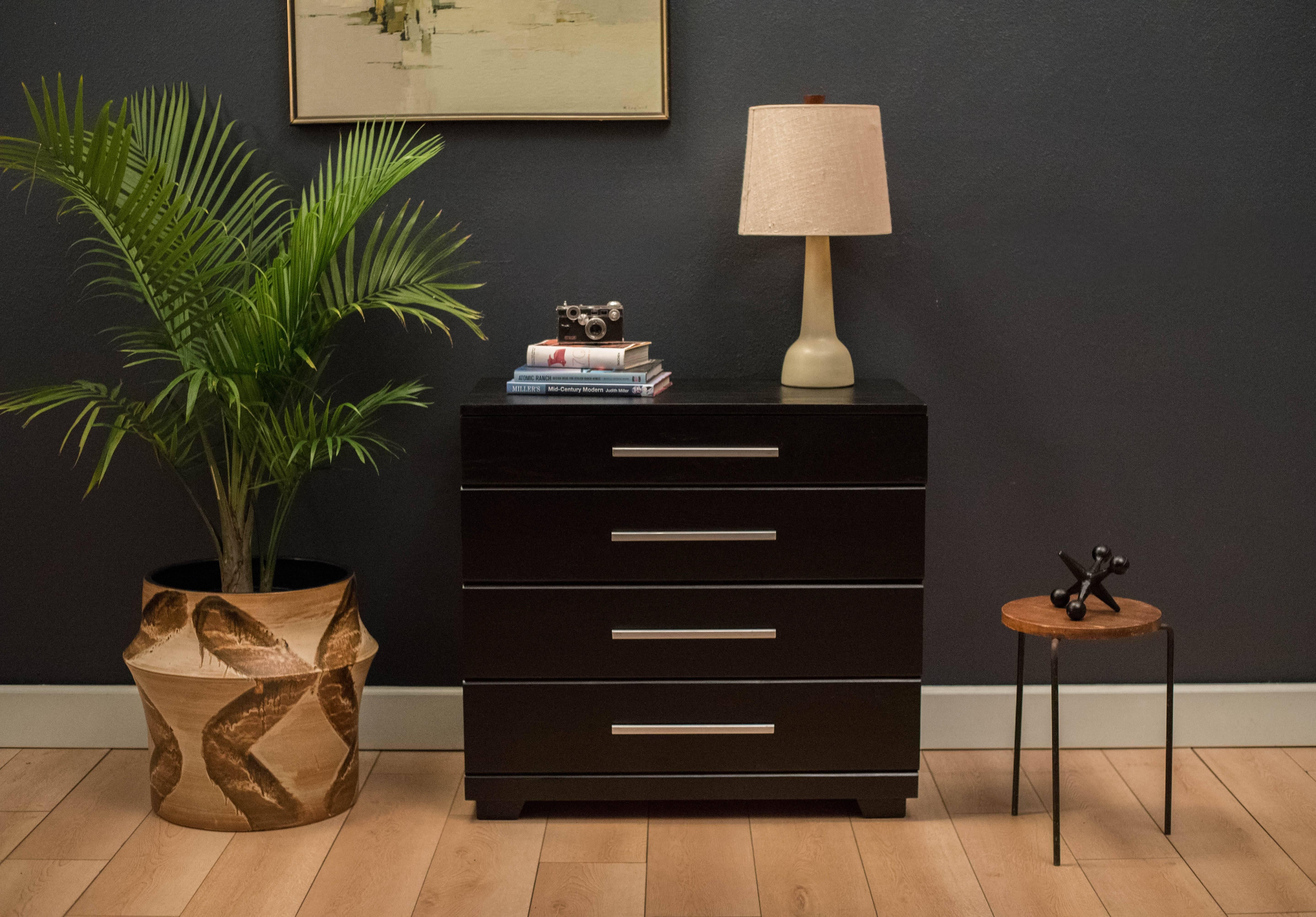 Mid-century dresser chest designed by Raymond Loewy for Mengel Furniture Co. in ebonized solid oak. This piece features four wide drawers with cast aluminum pulls.
