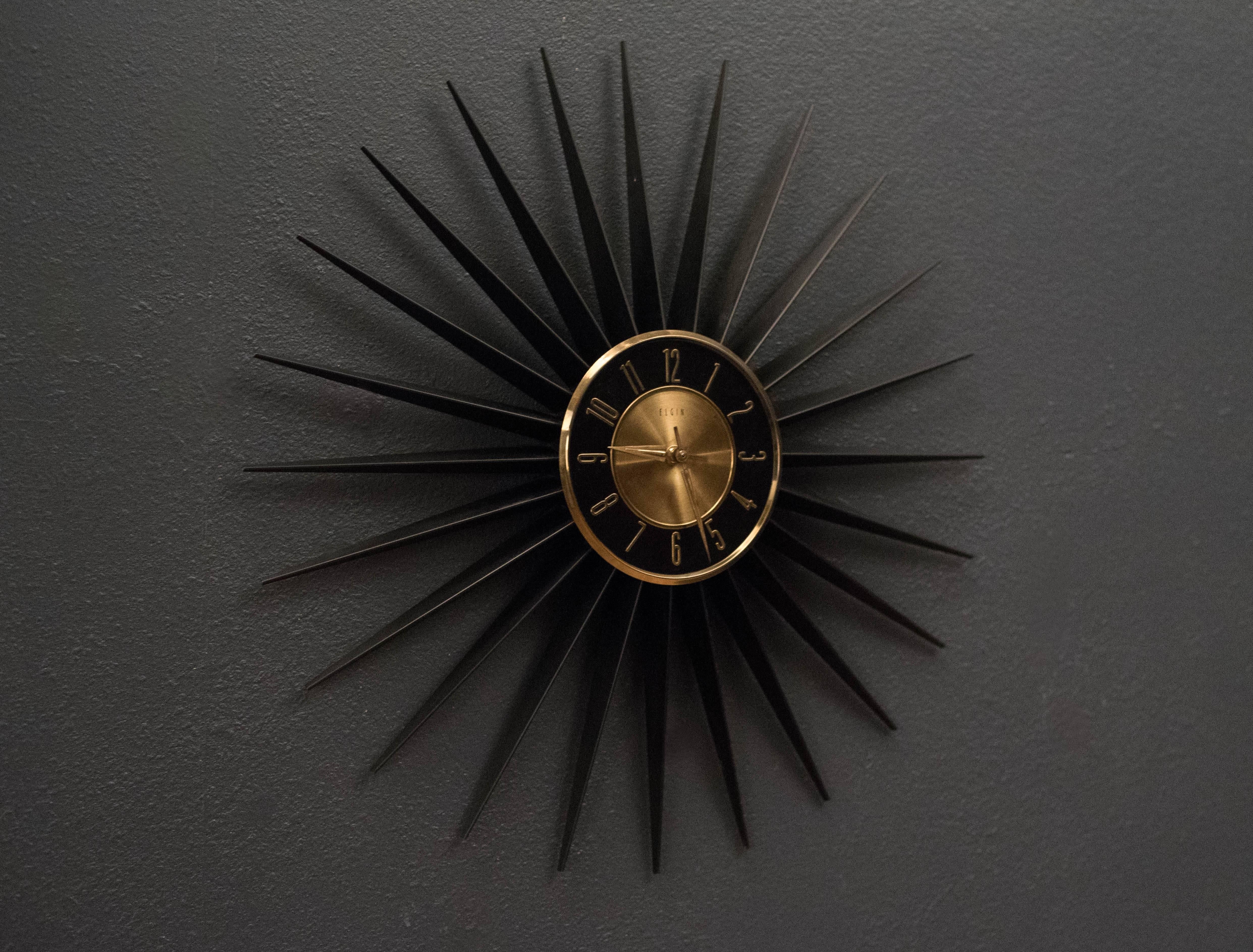 Mid-Century Modern sunburst clock, circa 1960s. This collectible piece is made by Elgin and has a brand new quartz movement. Runs on a single AA battery.