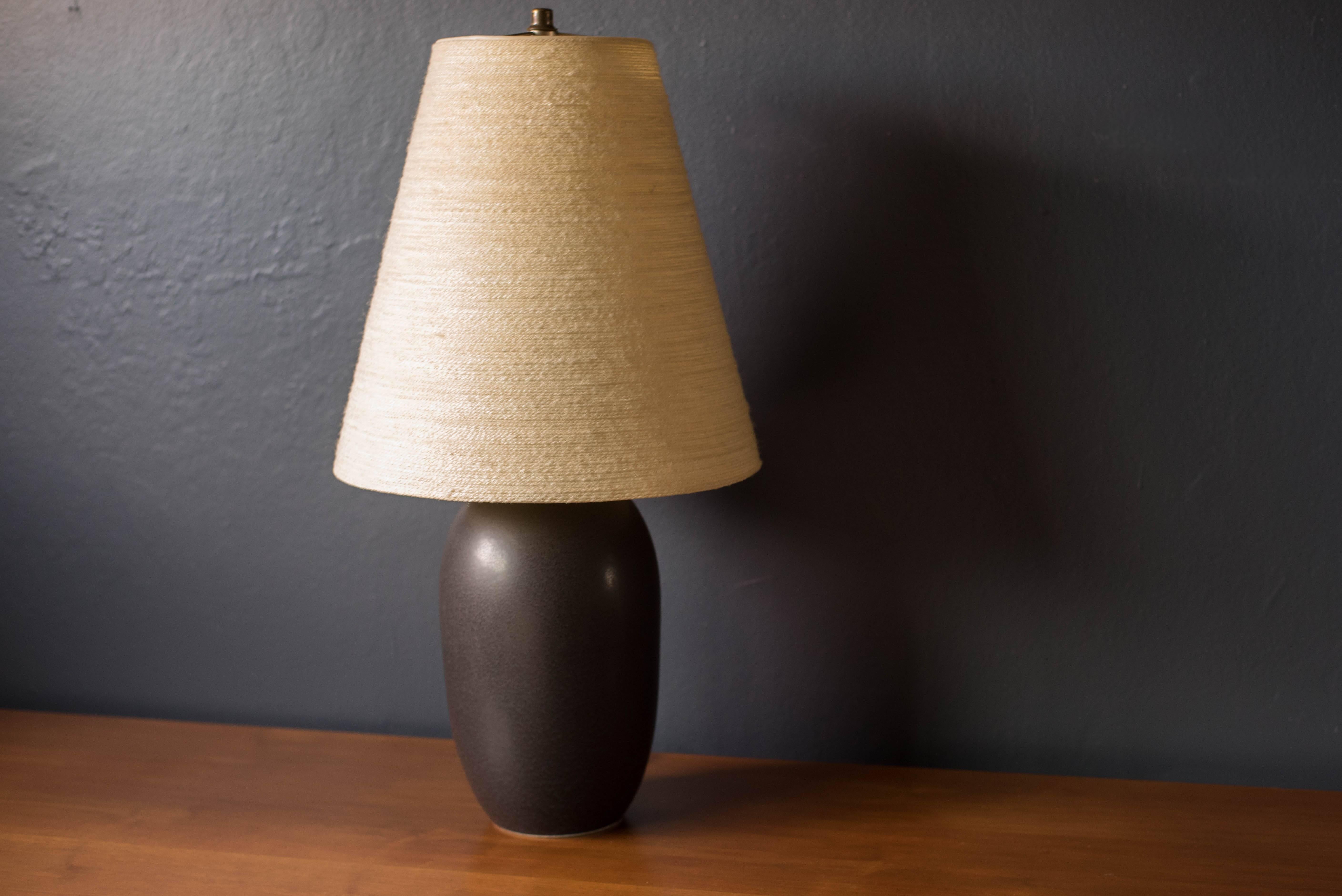 Mid-Century Modern pottery lamp by Lotte and Gunnar Bostlund. This piece features a speckled dark blue and black matte finish and includes the original fiberglass tapered shade. Functions with a three way switch.