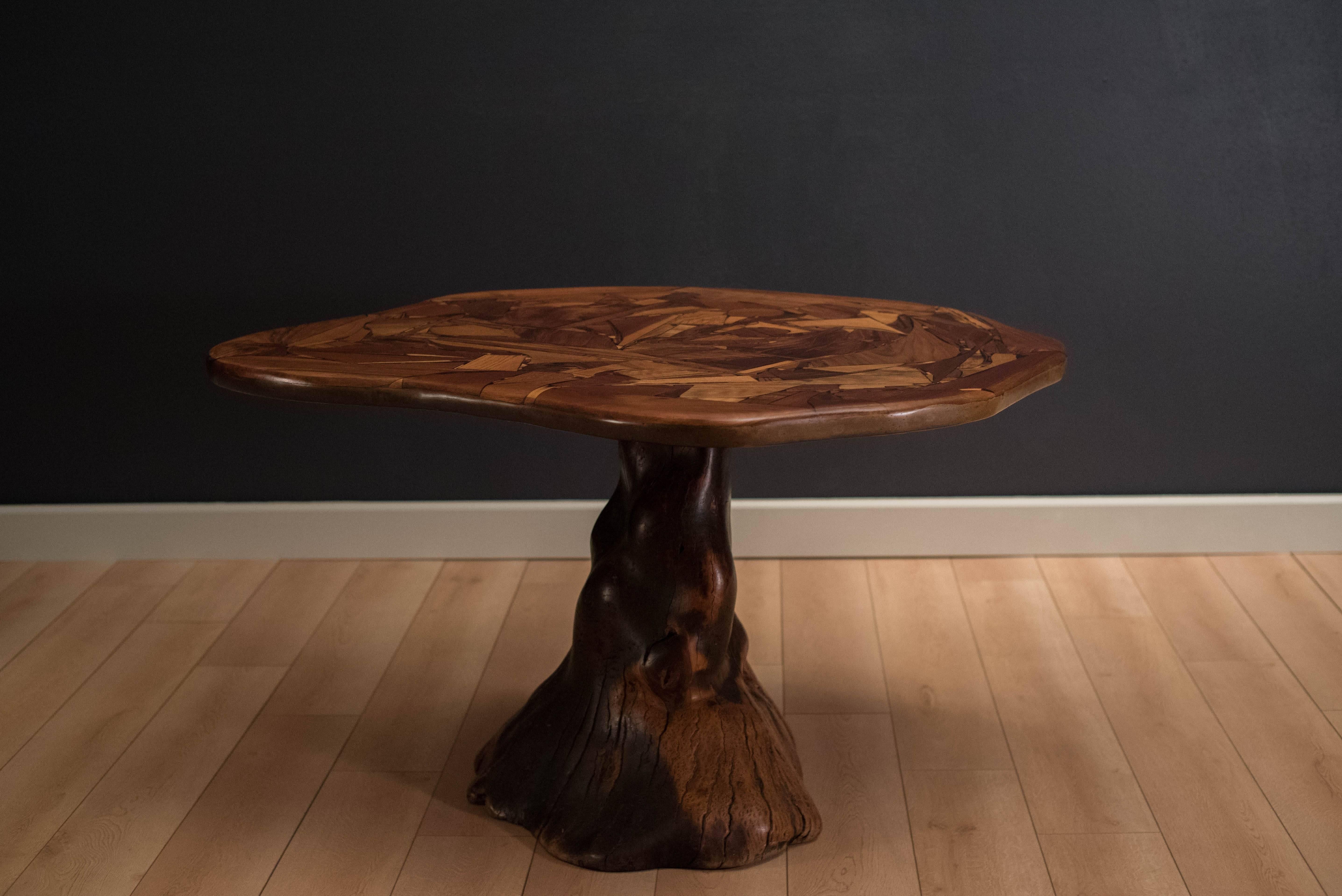 Mid-Century studio craft solid dining table. This free-form top displays a beautiful mosaic pattern of walnut, oak, mahogany and koa wood. Each wood piece is held together by resin and clear epoxy making an organic shape. Top rests upon a solid