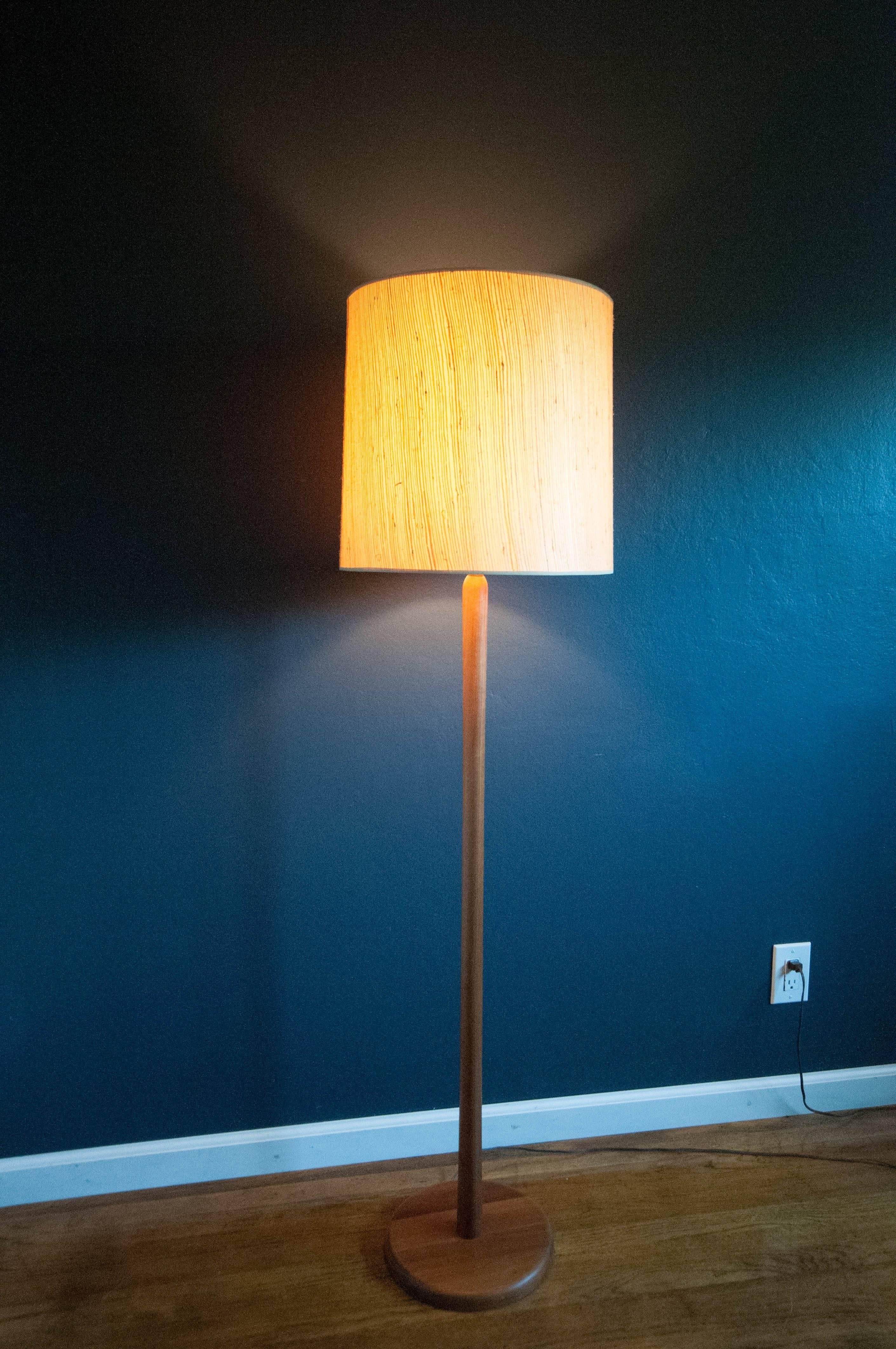Mid-Century Modern walnut floor Lamp designed by Jane and Gordon Martz for Marshall Studios. Features a three-way switch and includes original grasscloth shade and wood finial.