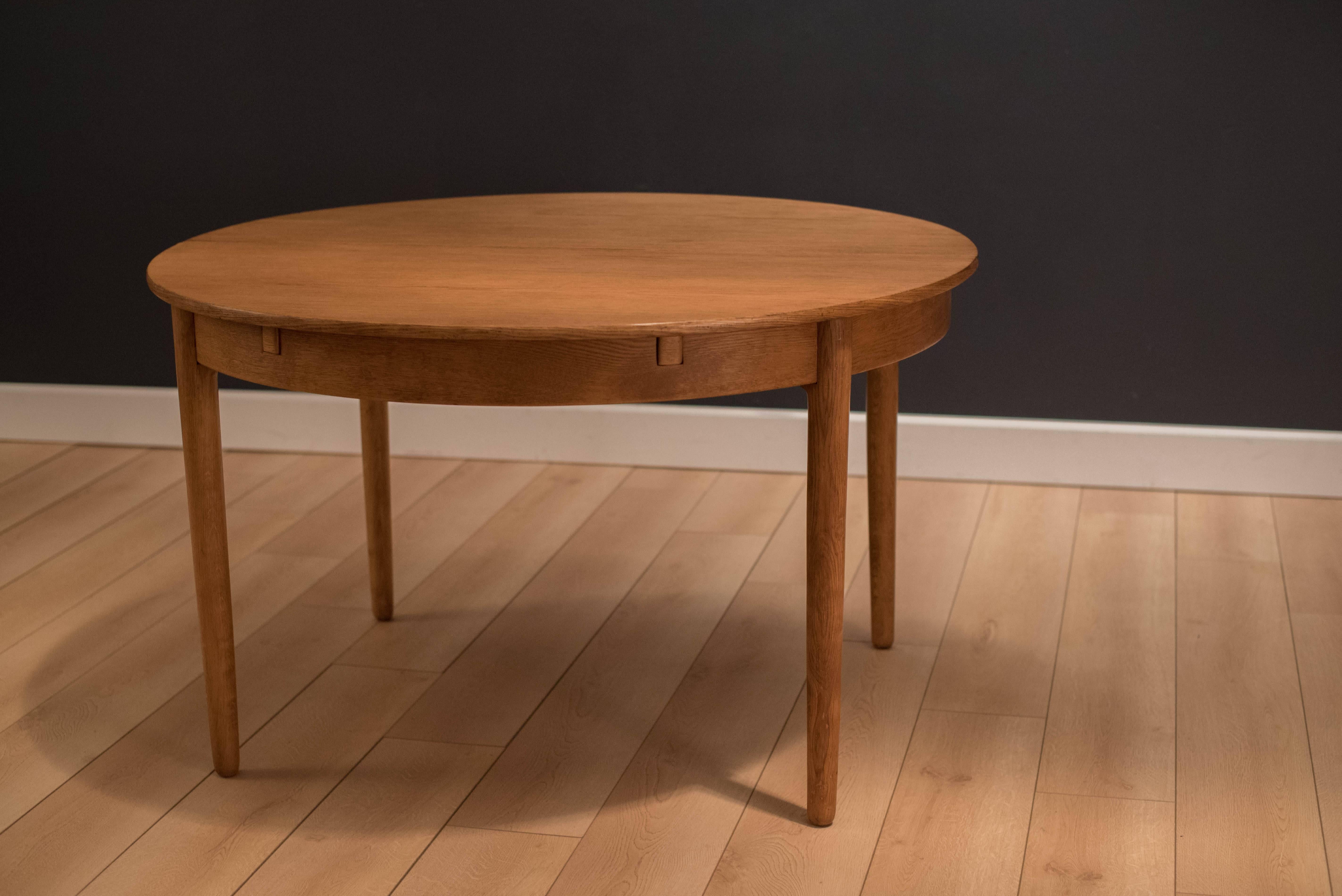 Mid Century Danish Dining Table designed by Hans Wegner for Andreas Tuck. This collectible piece displays excellent craftsmanship and is constructed of oak. Table comes with one extension leaf and is perfect for entertaining in small spaces. Extends