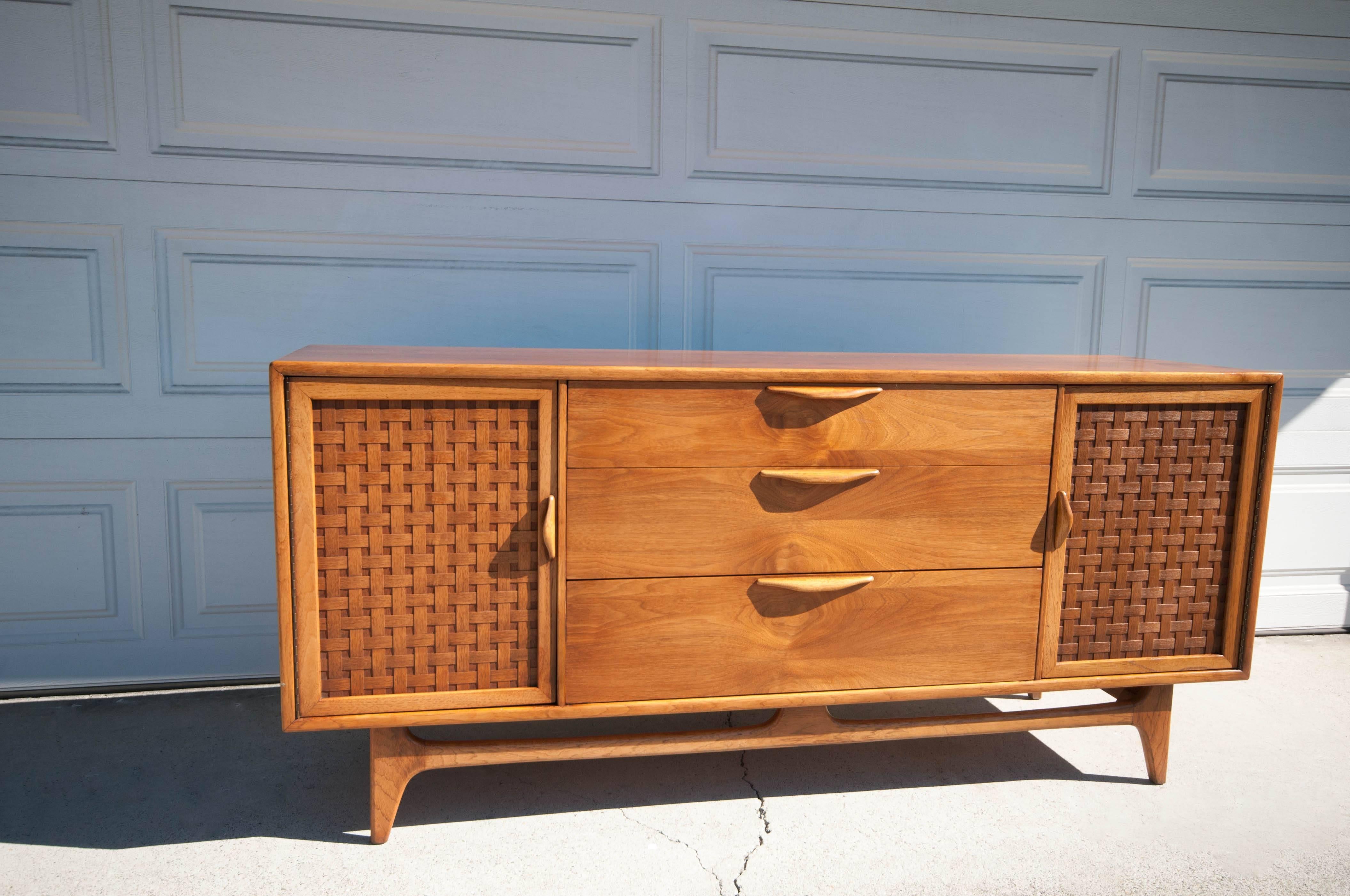 Mid Century Lane Perception Credenza in walnut and oak. This piece features three large dovetailed drawers with sculpted pulls. Signature basketweave doors reveal one fixed shelf and a drawers for each side. It is in great condition with minimal