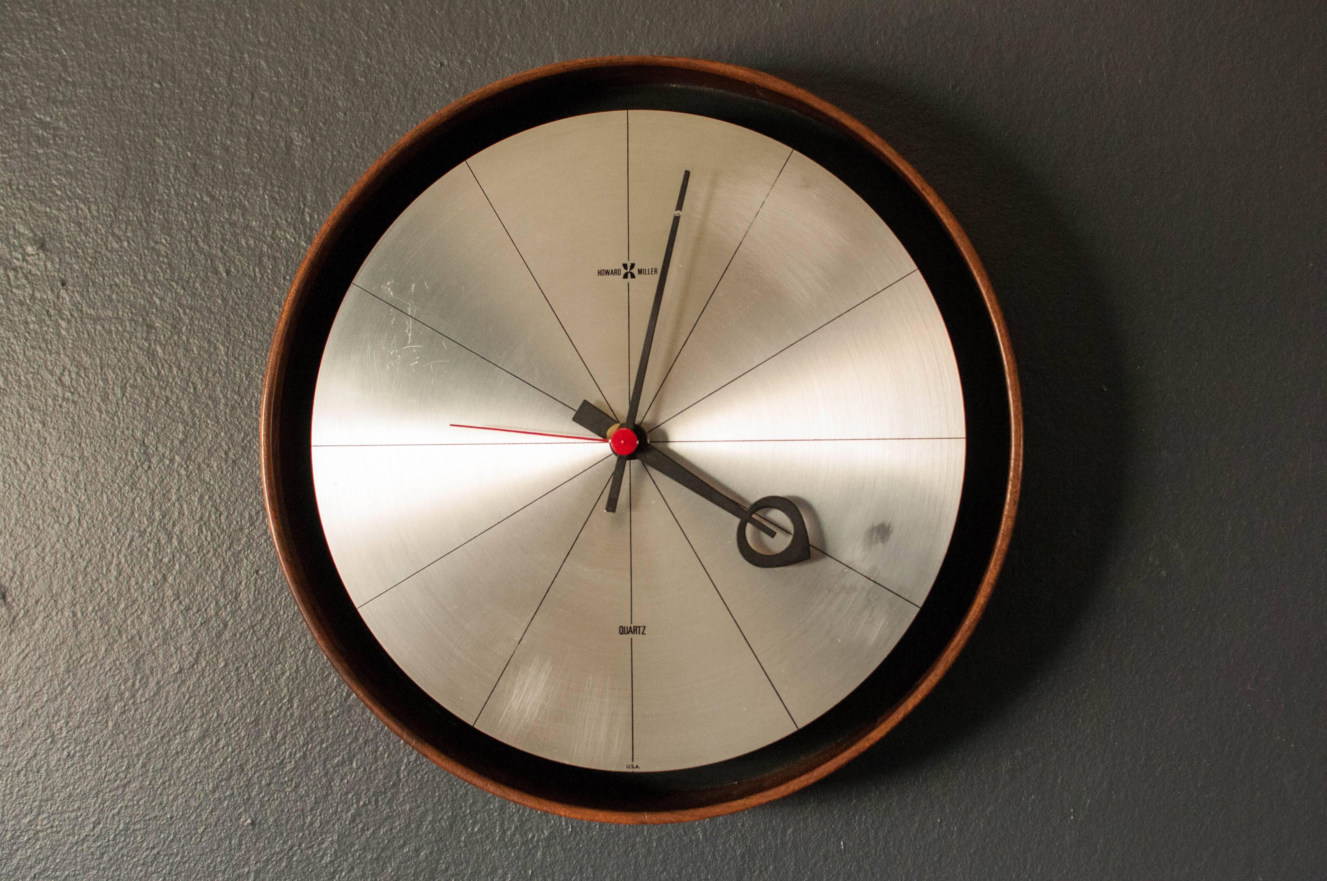 Mid Century Howard Miller Wall Clock by Arthur Umanoff. Designed with a surrounding walnut case, this modernist piece will look great with any home or office decor. Functions on one C battery and is in good working condition. 

