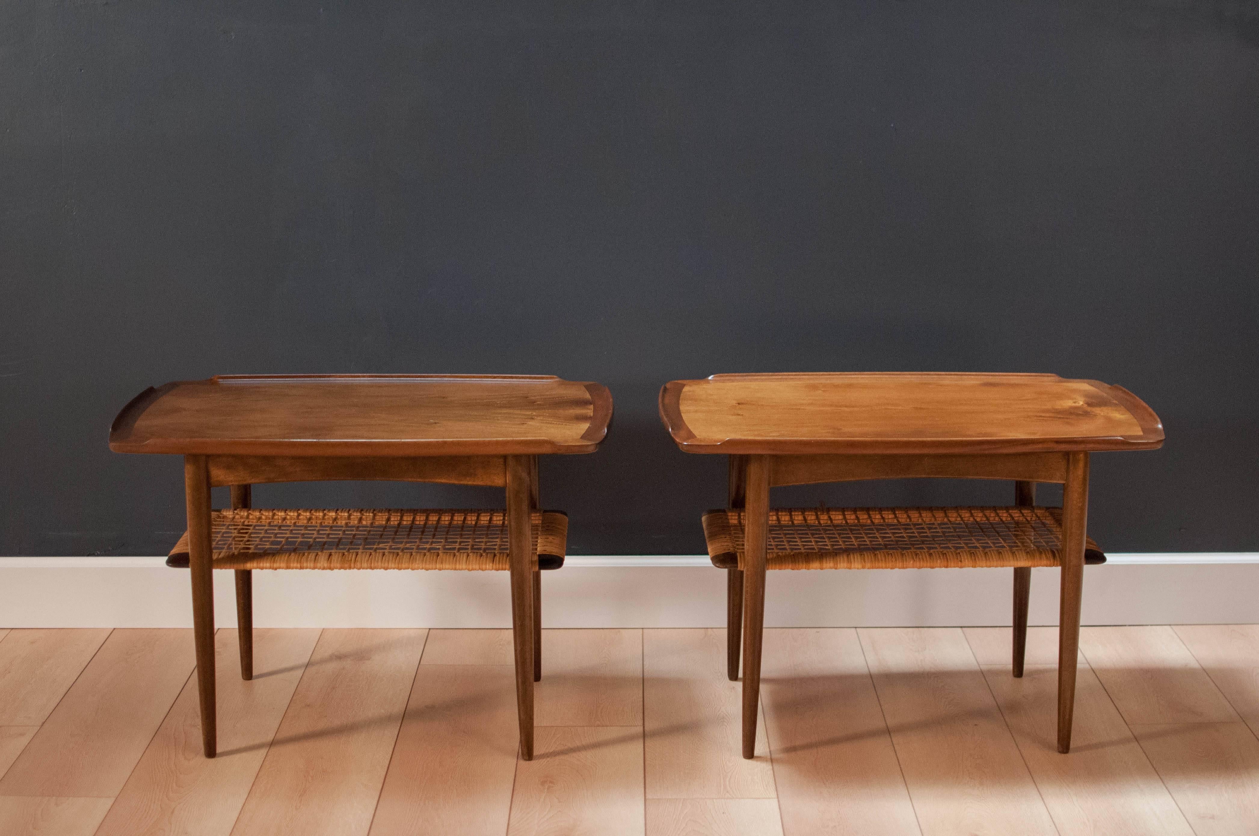 Danish pair of side tables designed by Poul Jensen for Selig. This set is made of walnut and displays sculpted raised edges with a two-tier magazine shelf made of cane. Price is for the pair. 

