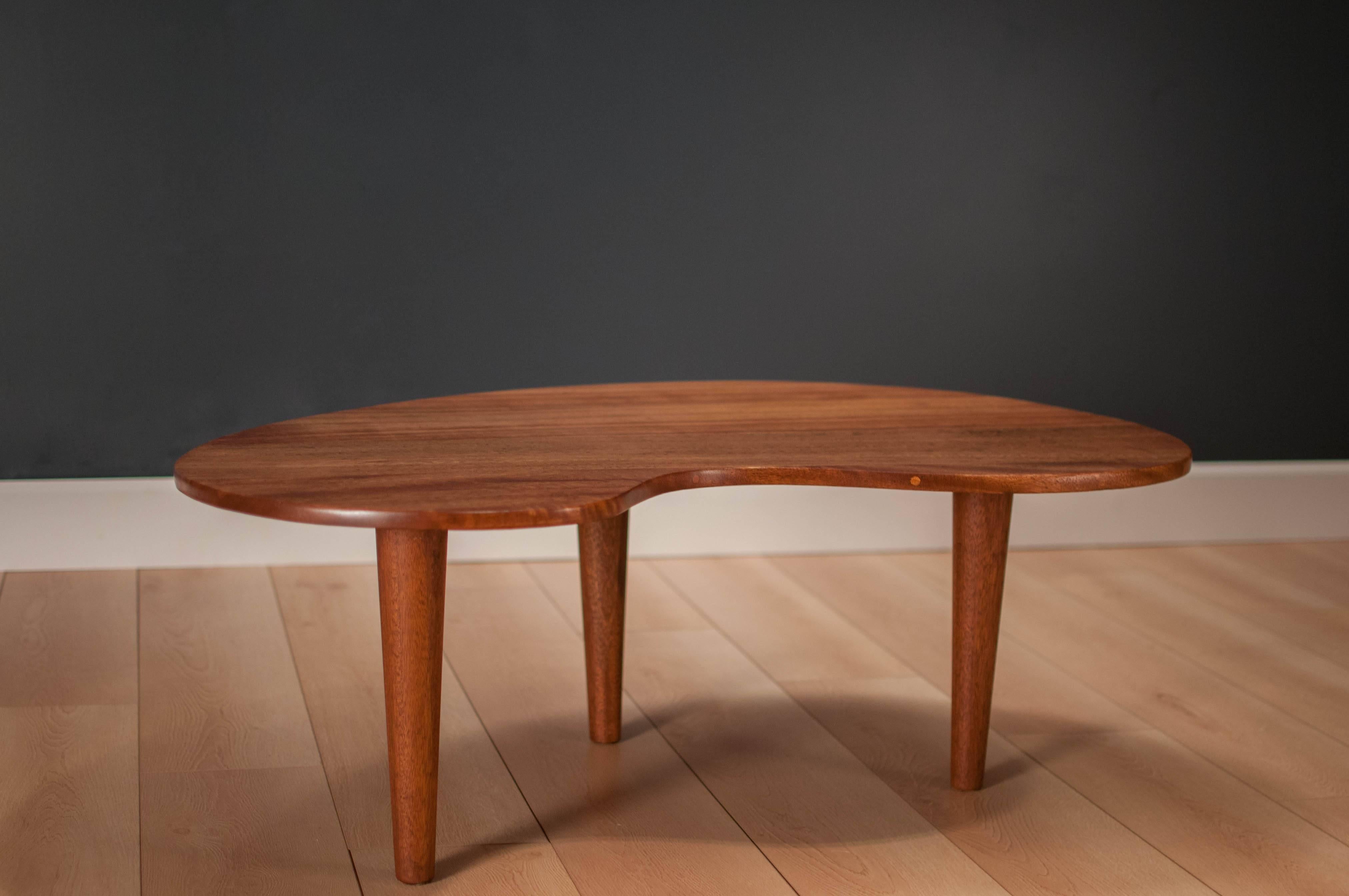 Mid-Century Modern kidney-shaped coffee table, circa 1960s. This piece has a solid planked mahogany top and three legged base. Makes for a great conversation piece.