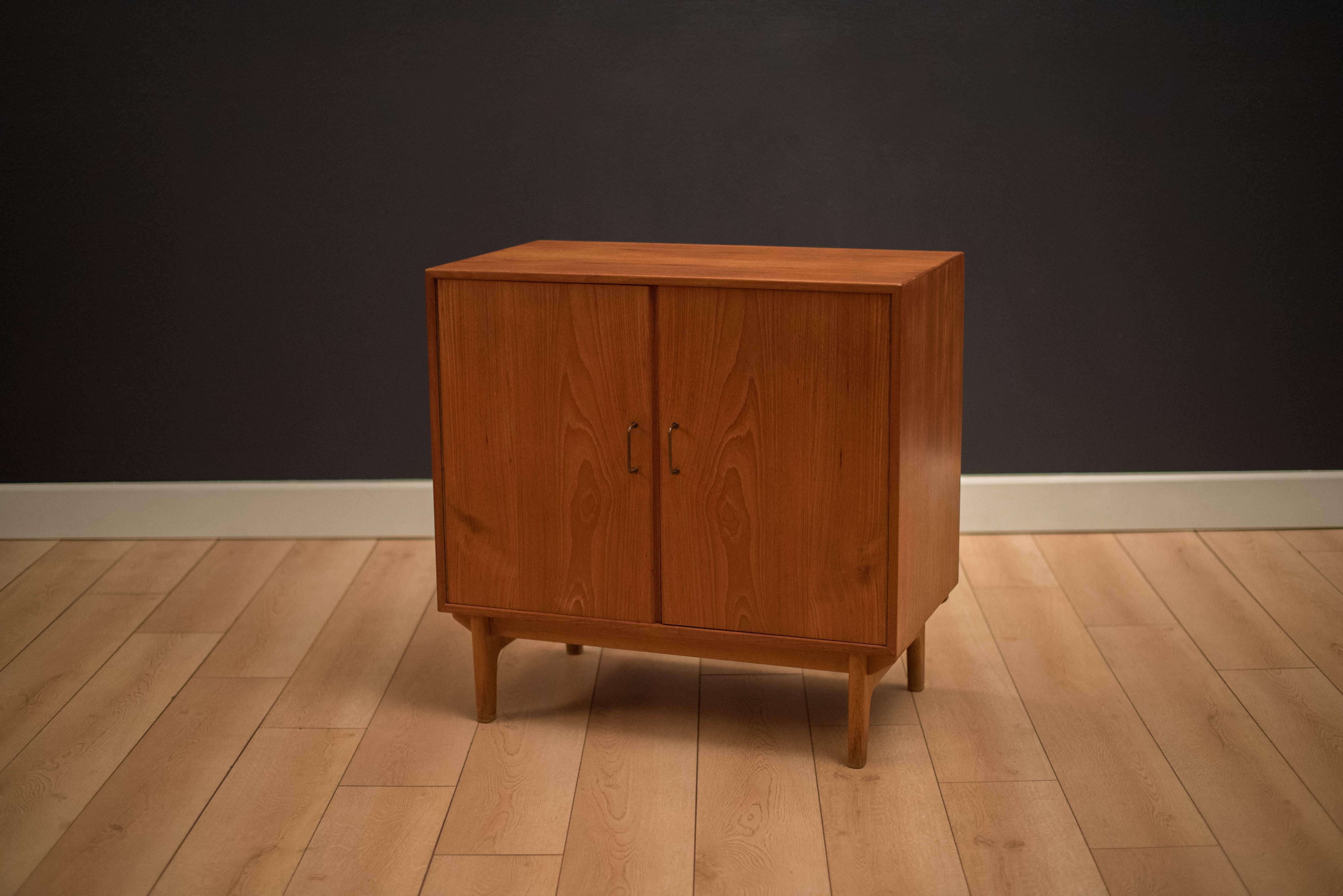 Danish modern teak cabinet designed by Torben Strandgaard with a solid oak base. Features pull-out doors with brass hardware and adjustable shelving. 
