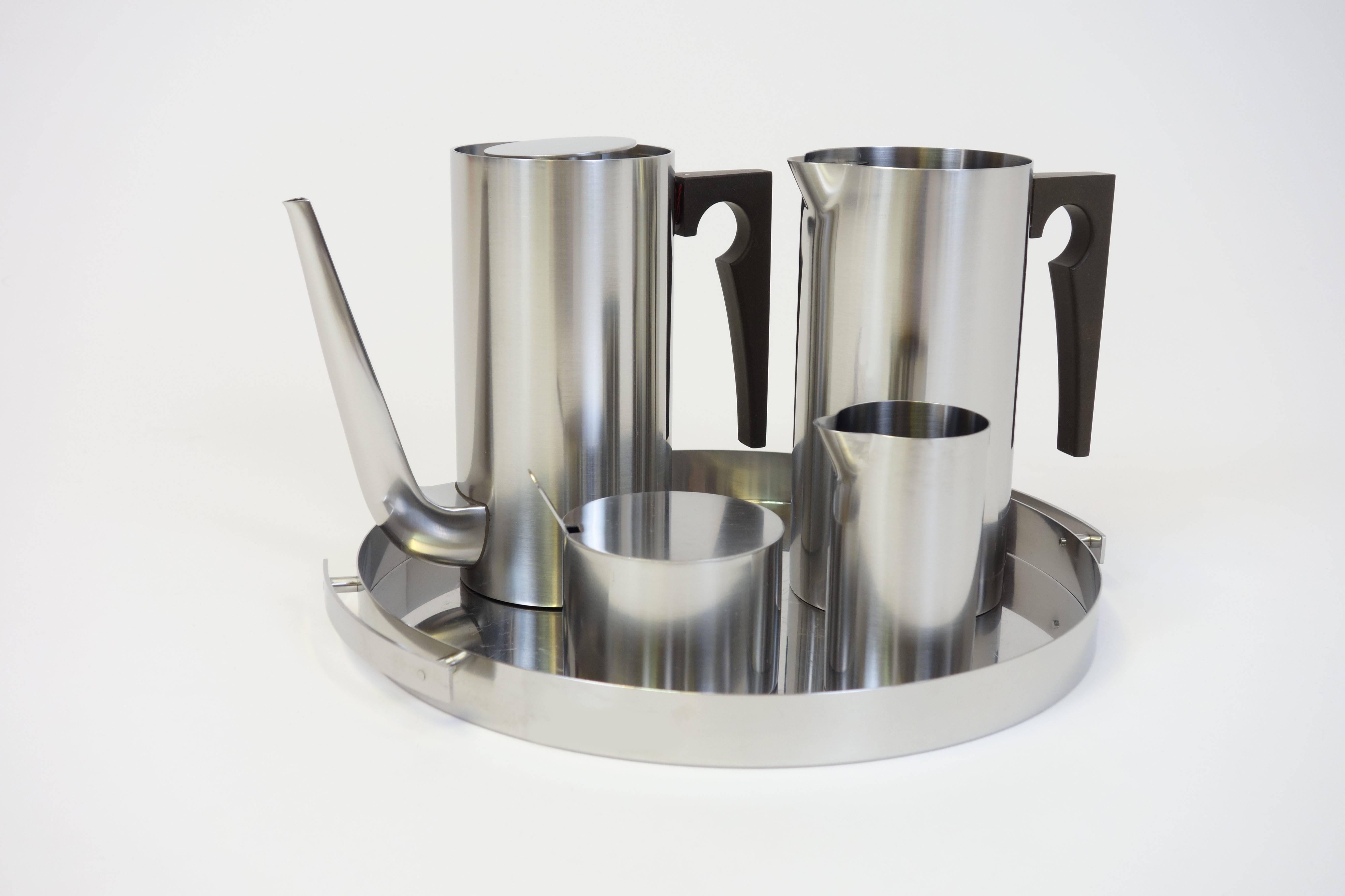 Moka set “Cylinda Line” by Arne Jacobsen for Stelton, 1967. Brushed stainless steel with black bakelite handles. We offer a moka pot, a milk jug, a sugar bowl with original spoon and a water jug including serving tray. Trend-setting for the