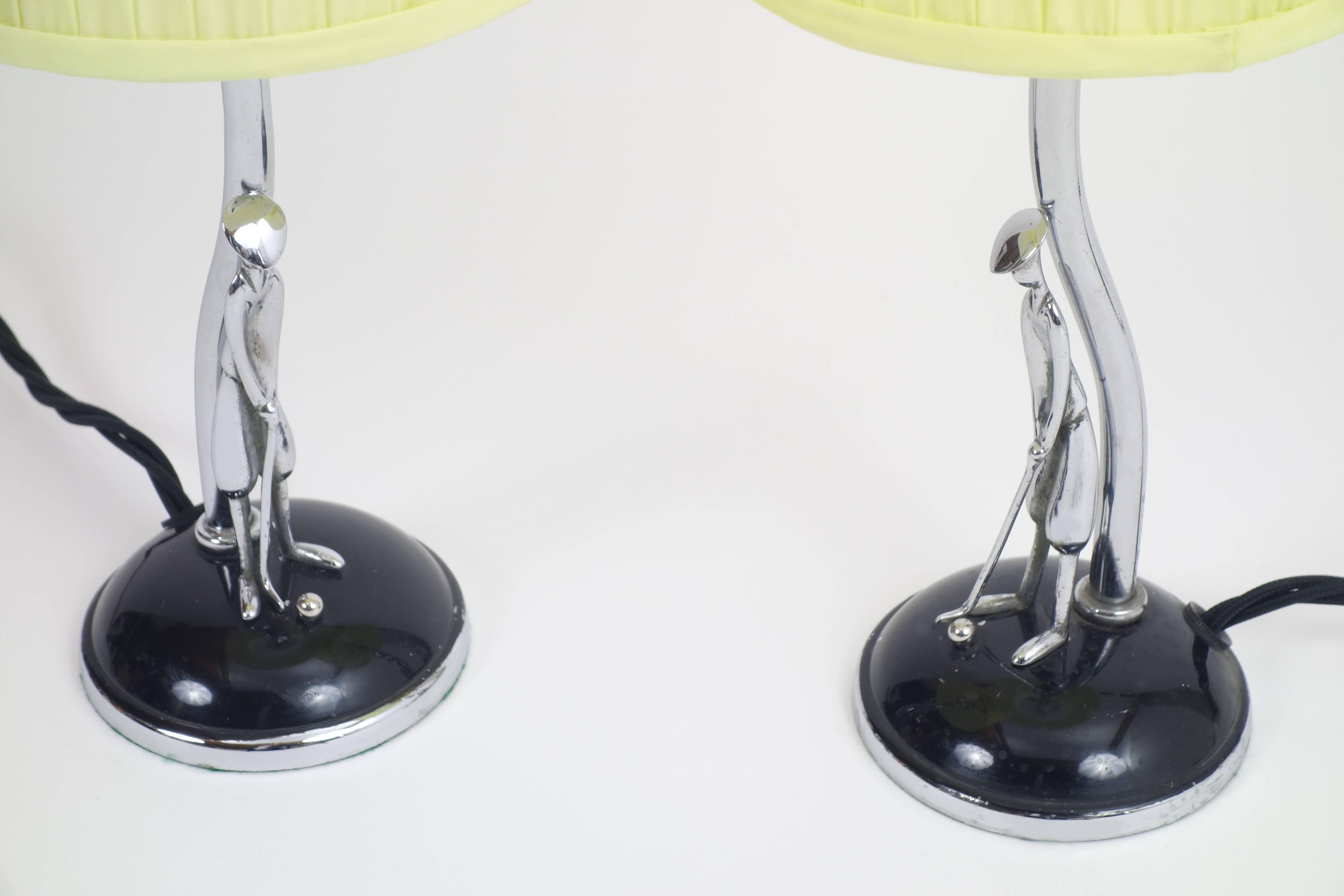 Pair of Hagenauer table lamps showing golf players on teeing ground in the 1930s. Gathered silk lampshades in lemon yellow hue.