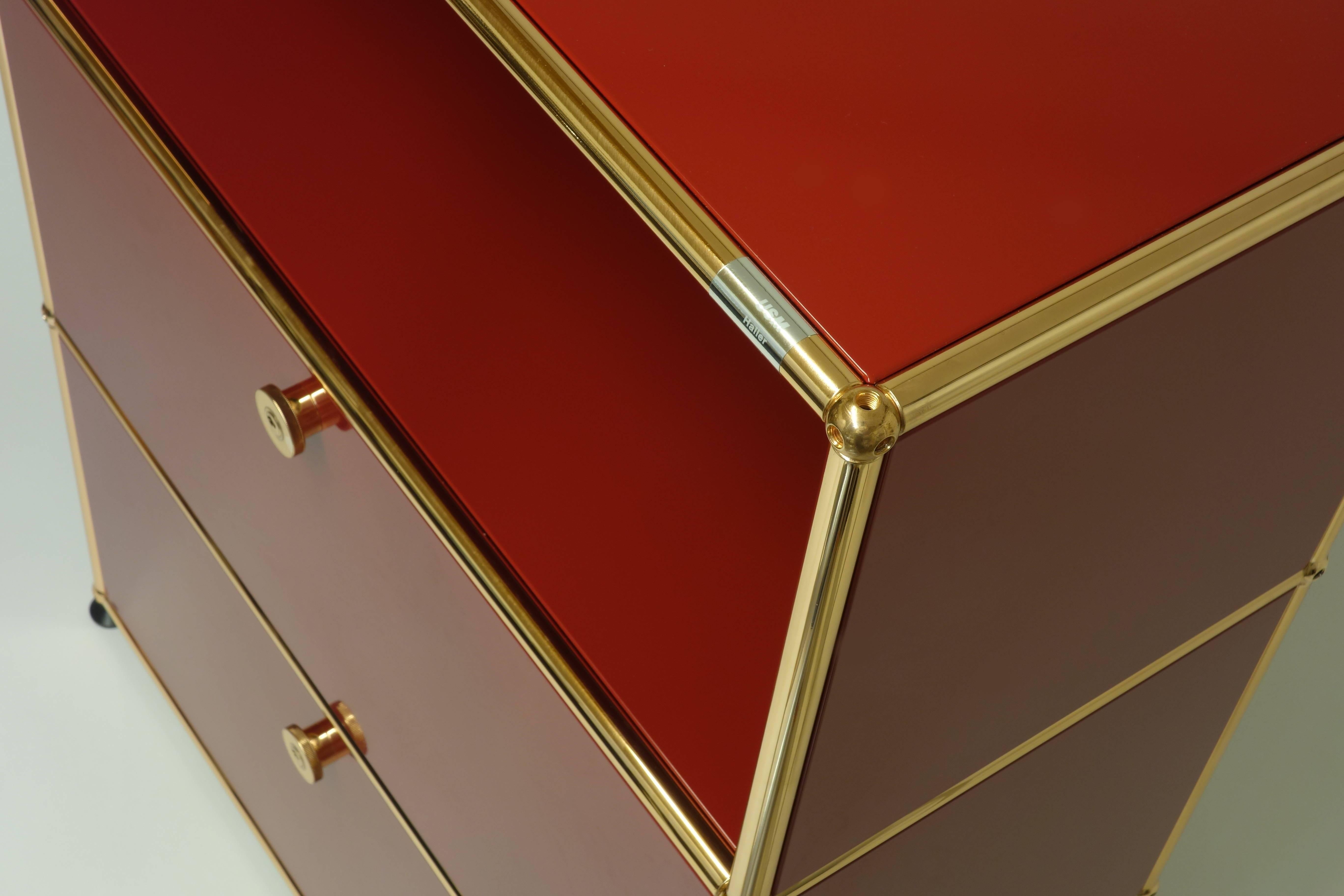 Chest of drawers by USM Haller with two panels and one open shelf in red color. Tubes, bowls and handles are copper plated and varnished.
