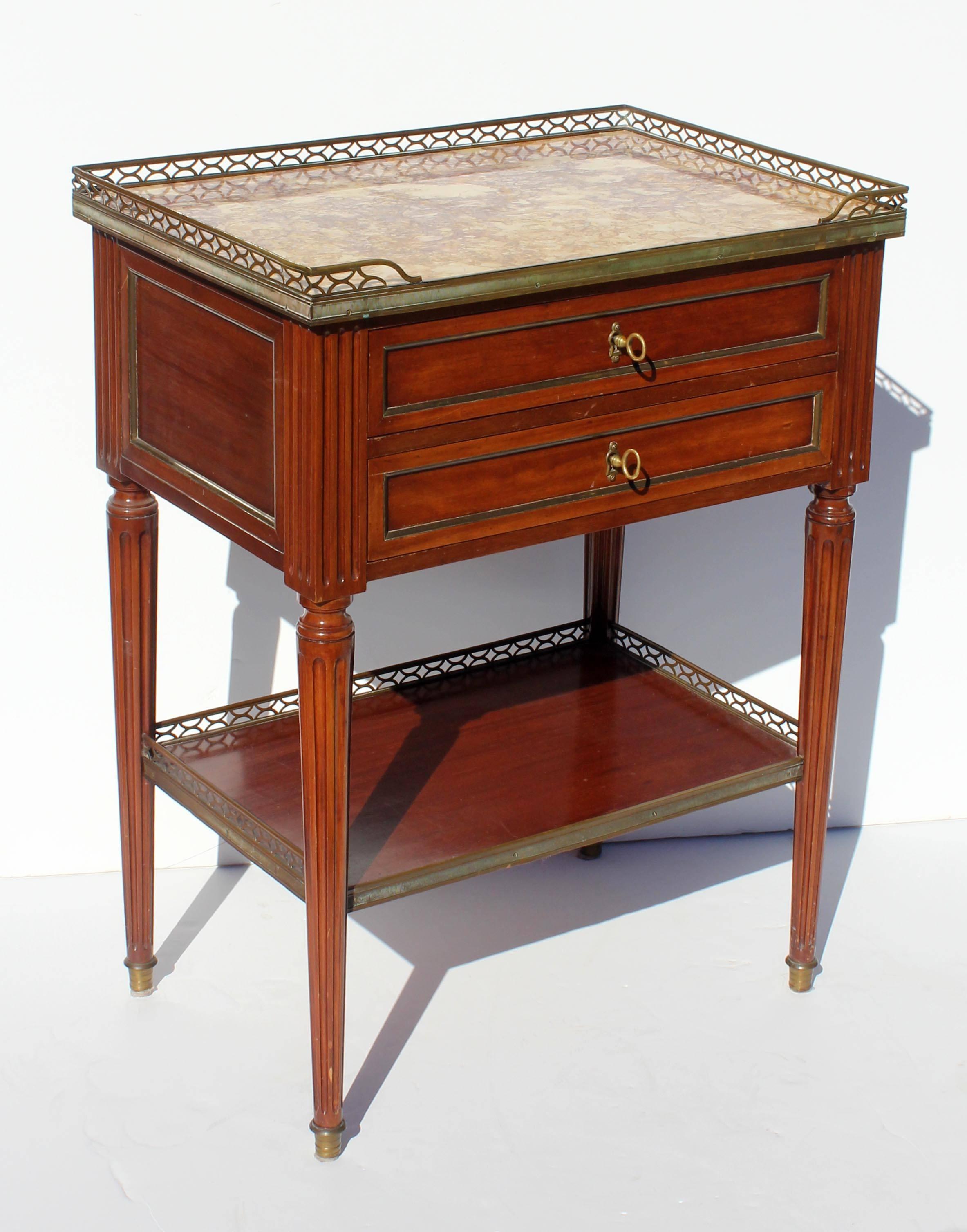 Antique French Louis XVI style marble top two-drawer side table. Mahogany with brass gallery and trim.
