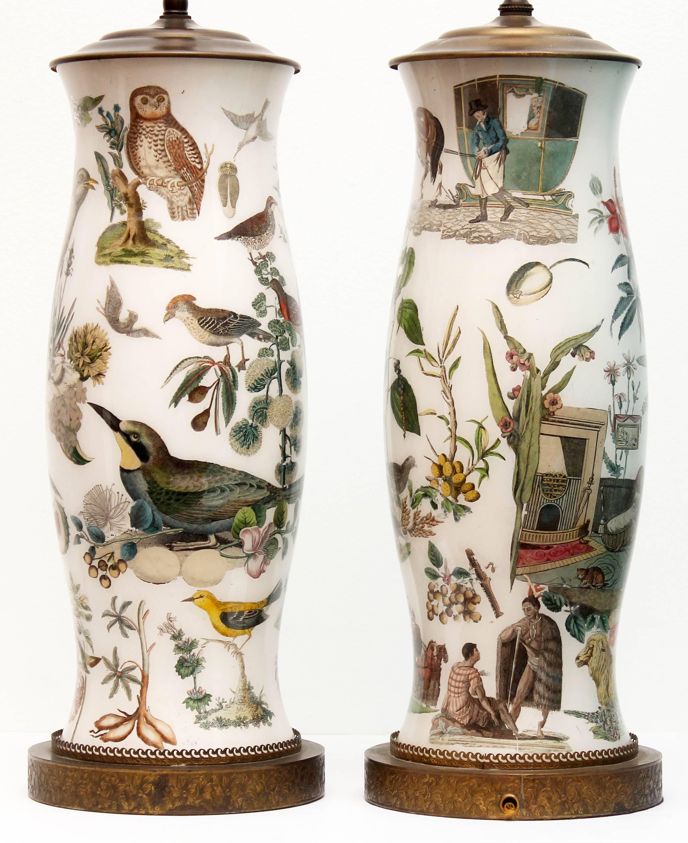 Pair of antique reverse decorated decalcomanie glass lamps. Bright and colorful, they are decorated with flora, fauna, and 19th century figures. Décalcomanie, is a decorative technique by which engravings and prints may be transferred. The bases are