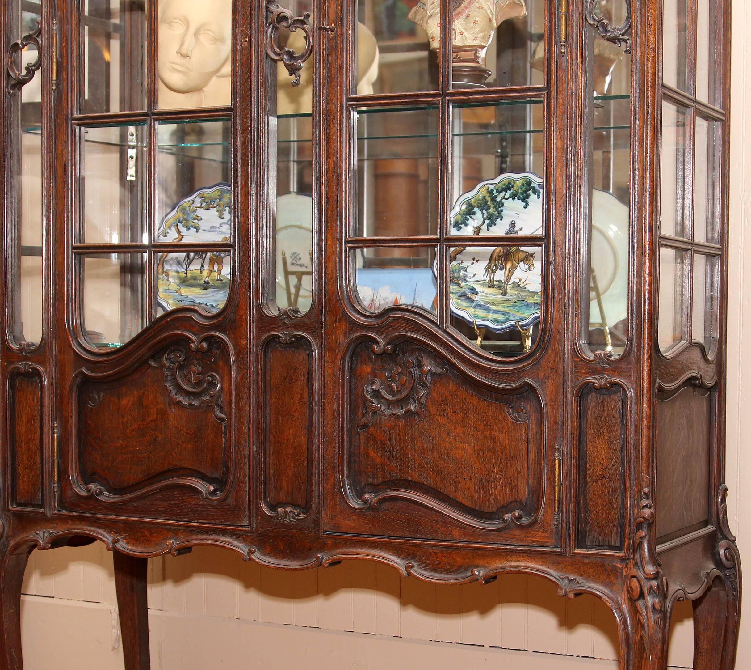 19th century French Louis XV style china cabinet. Carved solid quarter sawn oak. Interior fitted with light and plate glass shelving. Carved cabriole legs.An impressive 8