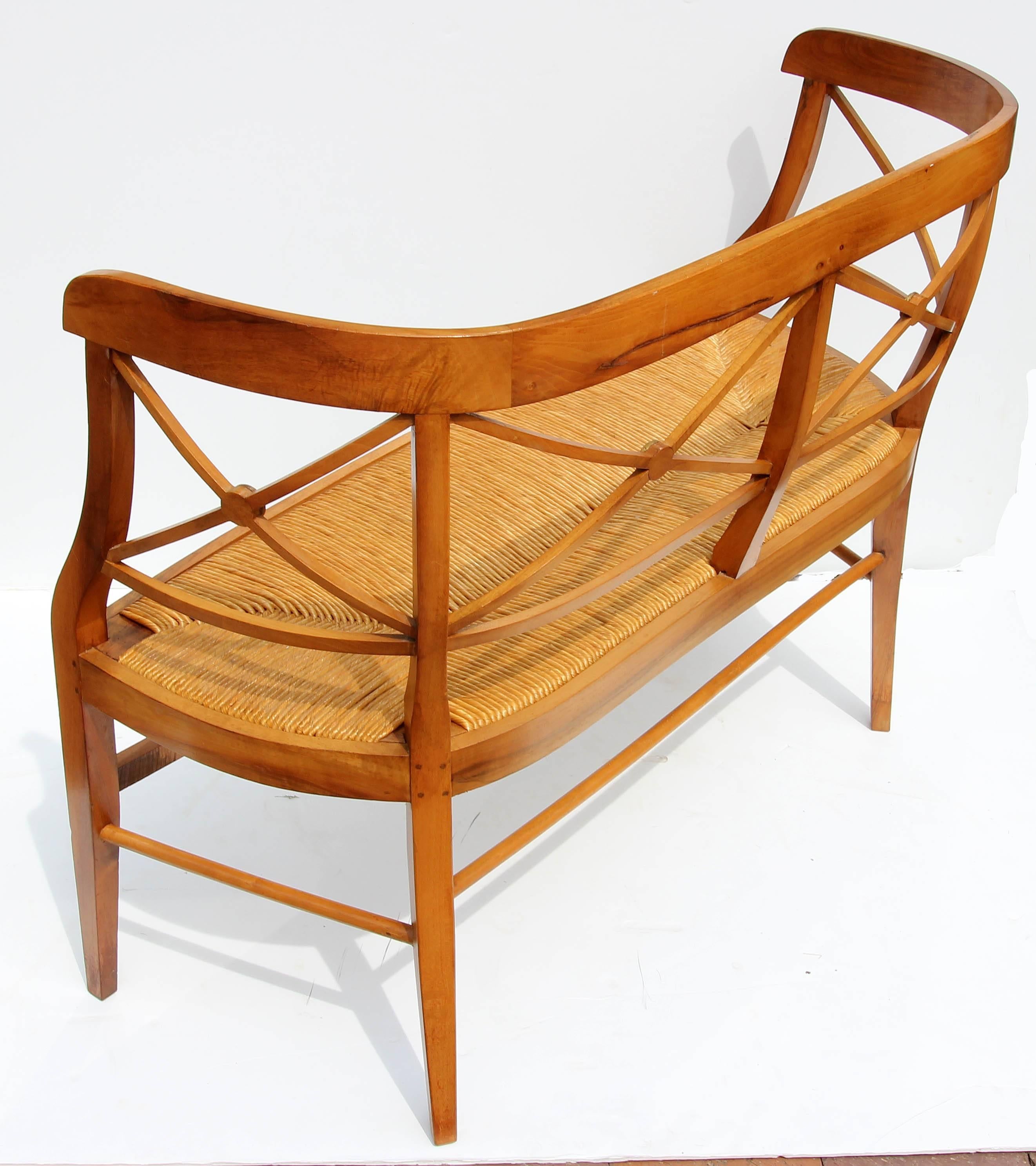 Neoclassical fruitwood settee with refined proportions. Wood and rush seat are in natural color. Mortise and tenon joints, early 20th century.