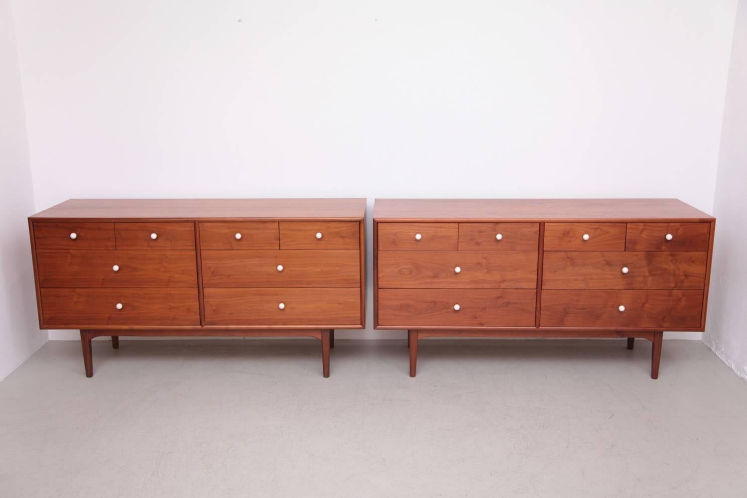 A beautiful pair of Mid-Century Modern dressers in walnut designed by Kipp Stewart and Stewart MacDougall for Drexel. Beautiful walnut grain. Original white porcelain drawer pulls in excellent condition.