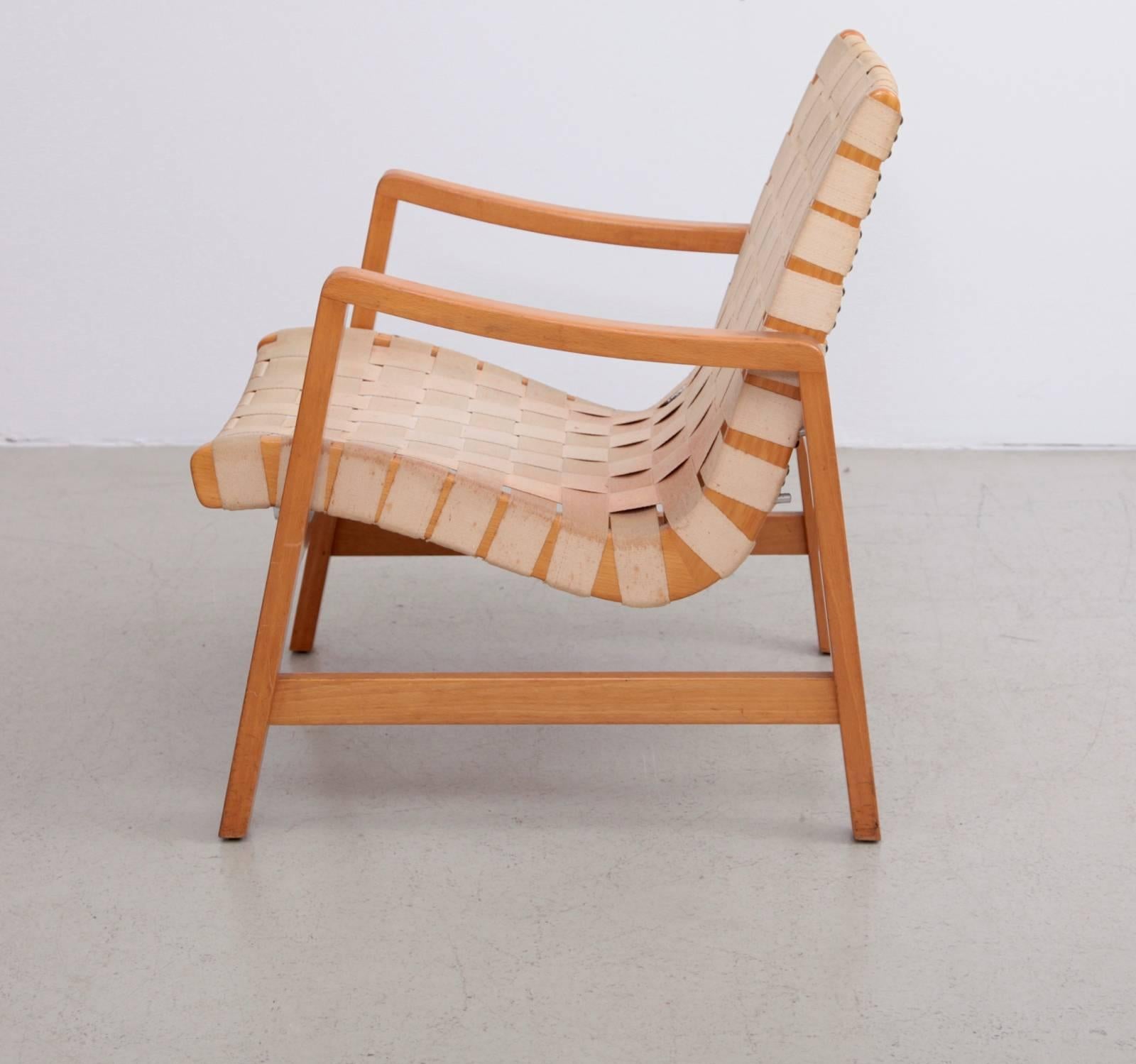 Early Jens Risom armchair by Vostra (German licensed and labeled) with off-white original webbing. The chair has two possible positions. Occasional and lounge chair height. Very good vintage condition.