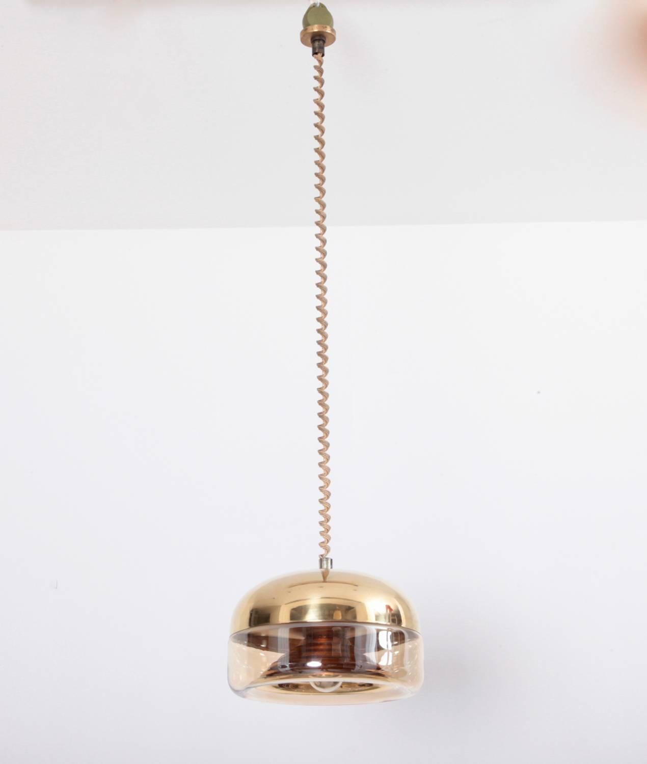 Beautiful Castiglioni style high quality brass and glass pendant with a height adjustable role system that is dated 1972. The glass has a gold plating and the top is solid brass.

Original cable and one x E27 / model a bulb.
To be on the safe side,