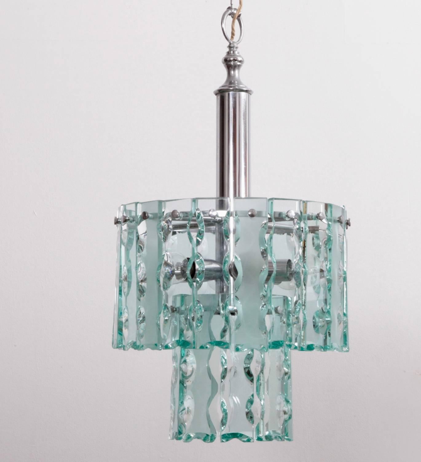 Bold two-tier Fontana Arte style chandelier which consists of 36 thick slabs of clear glass and flat glass on chromed hardware. Each slab is hand-cut and hand-chipped - a radical physical break away from traditional crystal glass making. Six E14 and