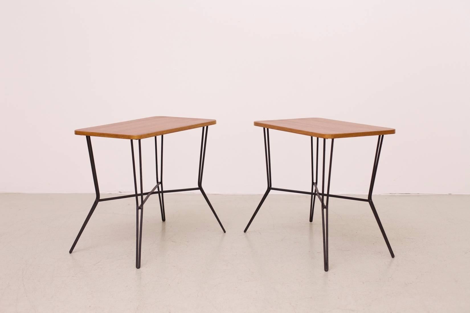 A set of two stunning french 50's coffee tables / side tables with wooden table tops on a black metal base in the manner of Jean Royère. They are in perfect vintage condition.