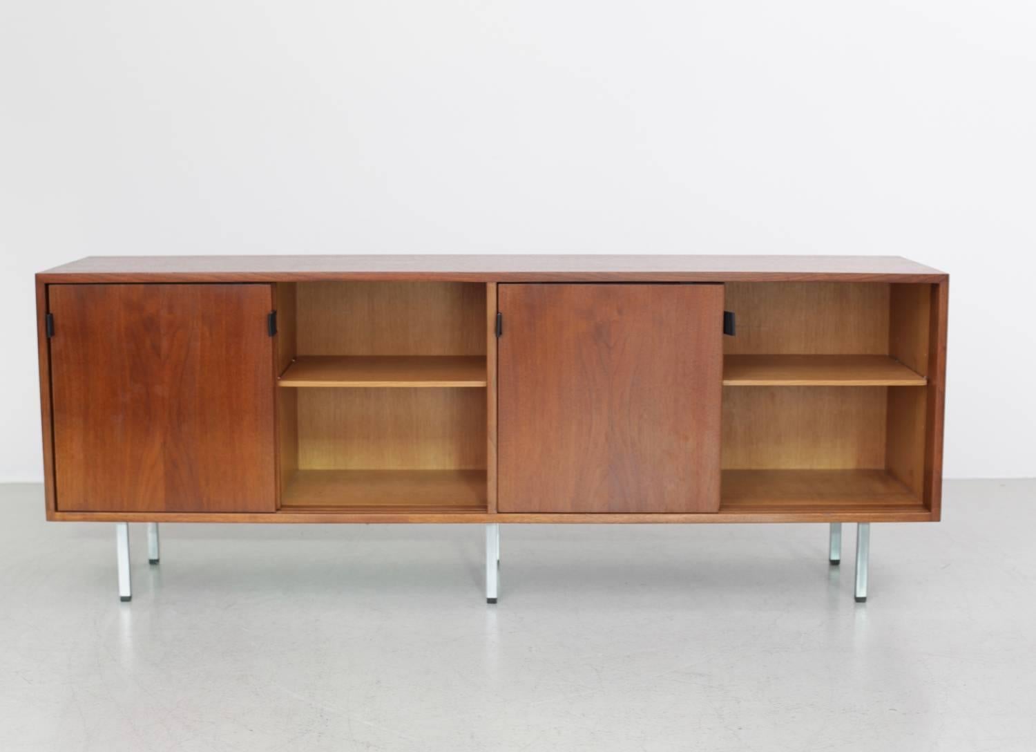 Florence Knoll credenza in walnut with leather pulls and metal legs. There are four compartments. Three adjustable shelves and on the left side one extensible.
 Gingerly restored and in excellent condition!

