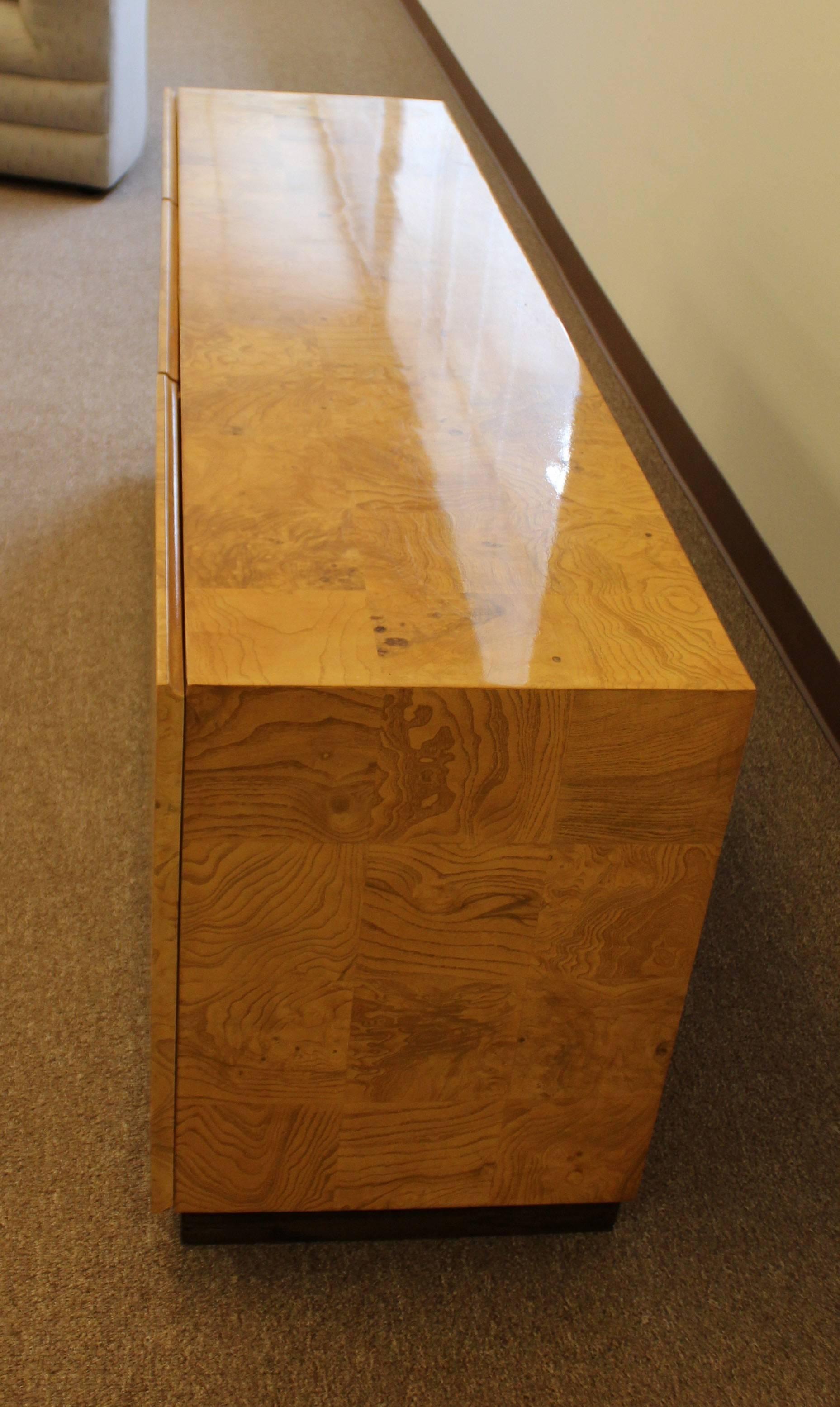 Simply magnificent burl wood credenza attributed to Milo Baughman for Thayer Coggin. The three doors open to reveal four pull-out drawers and a shelf. In excellent condition. The dimensions are 66