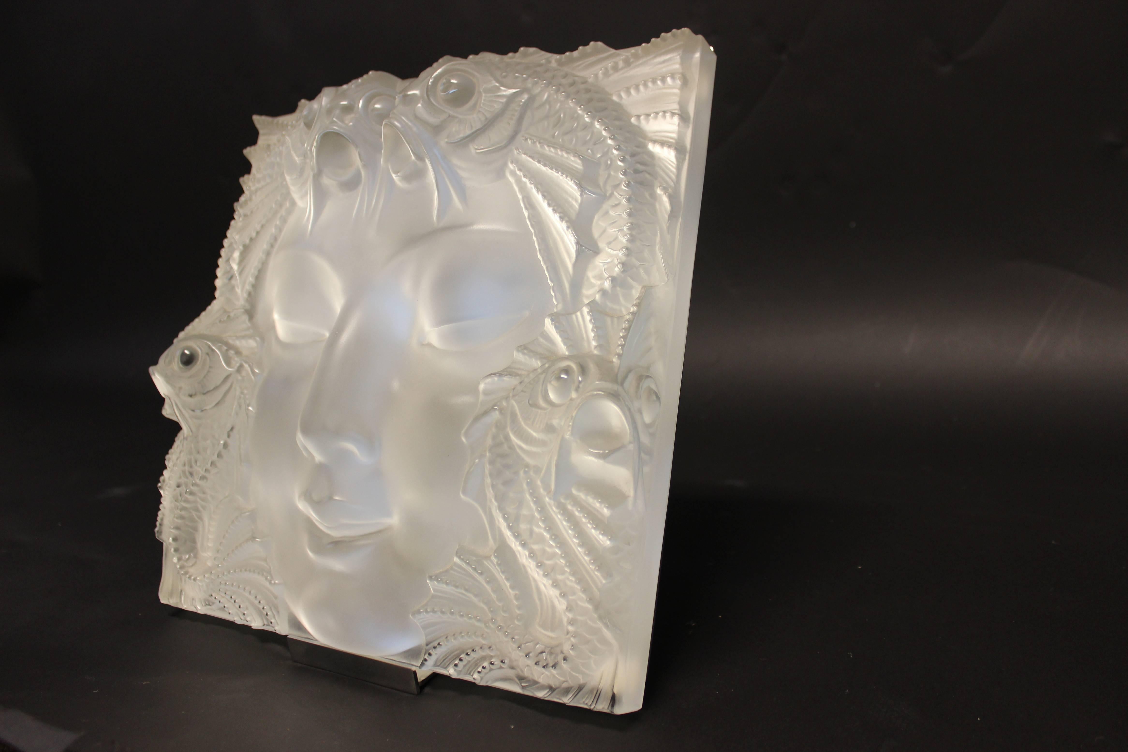 Lalique frosted glass mask. This work of art depicts a woman's face surrounded by four dynamic fish, which continue on the reverse side of the mask. This masterpiece measures to be 12.5