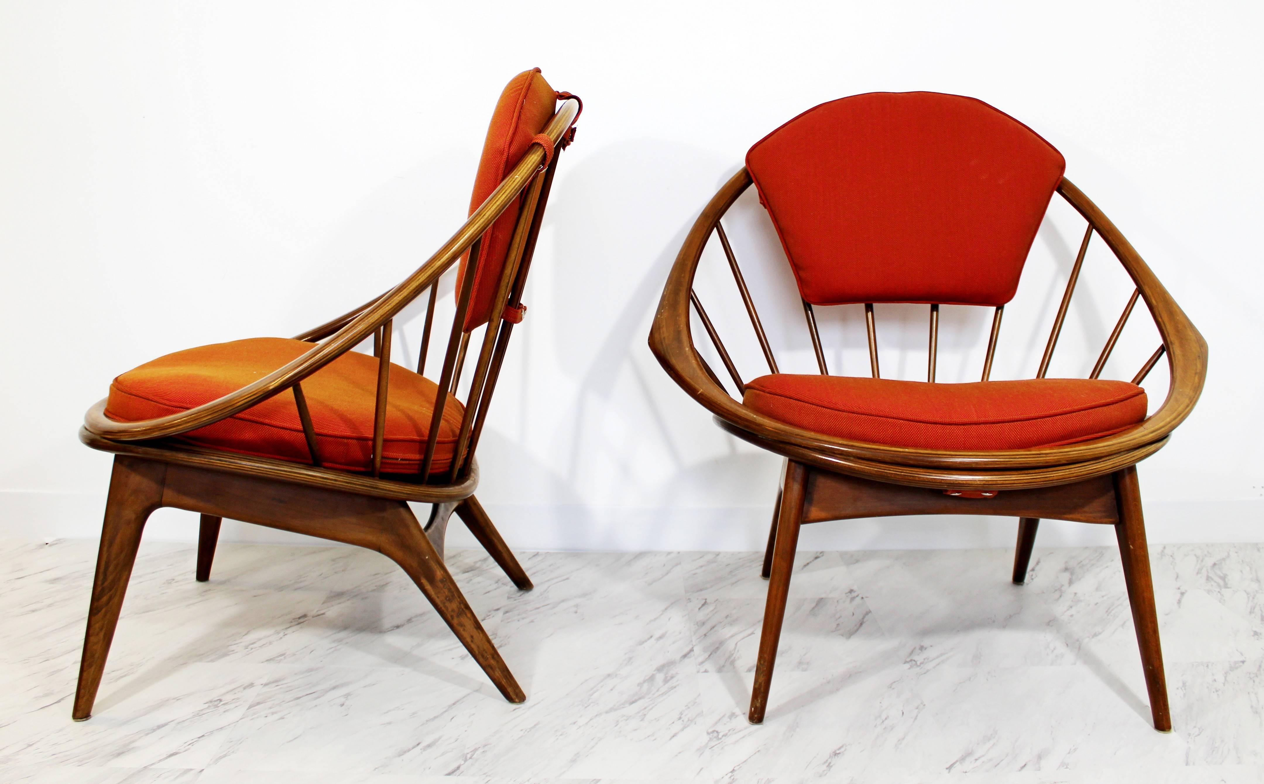 Absolutely stunning pair of Ib Kofod-Larsen hoop armchairs. This sensational pair of chairs have orange fabric, peppered with olive green dots, new straps and are in excellent condition. Each sculpted piece of furniture measures to be 34