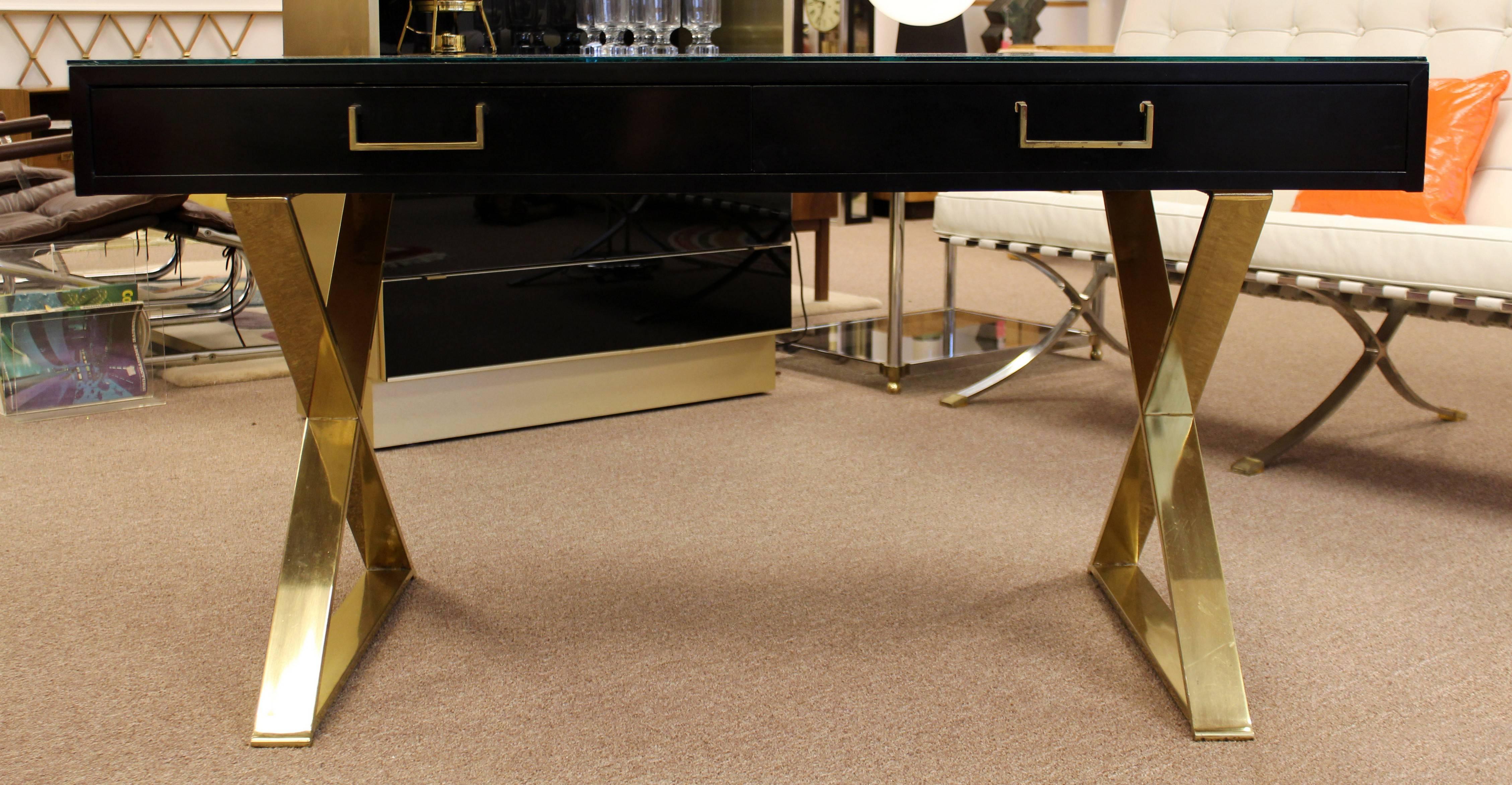 Beautiful black lacquer desk, on flat brass legs and with a glass top, by Milo Baughman. In excellent condition. The dimensions are 54