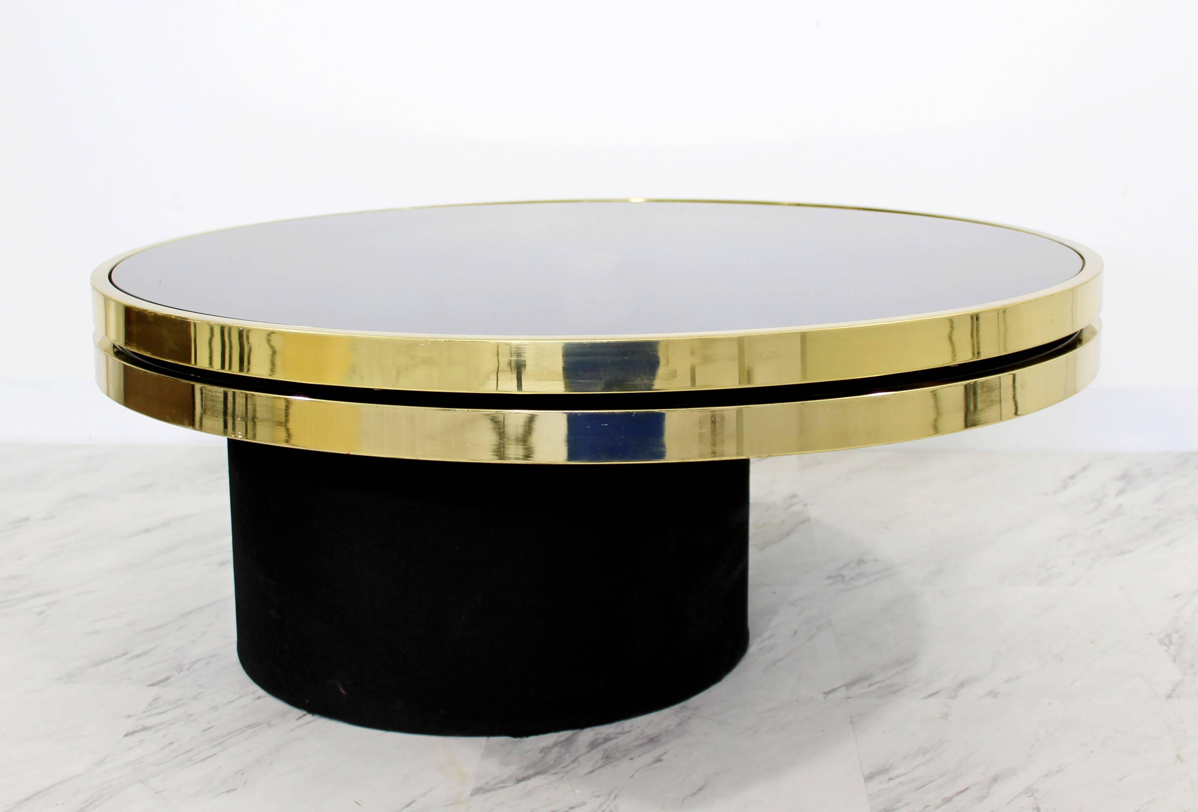 For your consideration is a magnificent, swivel coffee table, with two brass and smoked glass tiers, by the Design Institute of America, circa the 1970s. Swivel mechanism works flawlessly and the top rotates with ease. In excellent condition. The