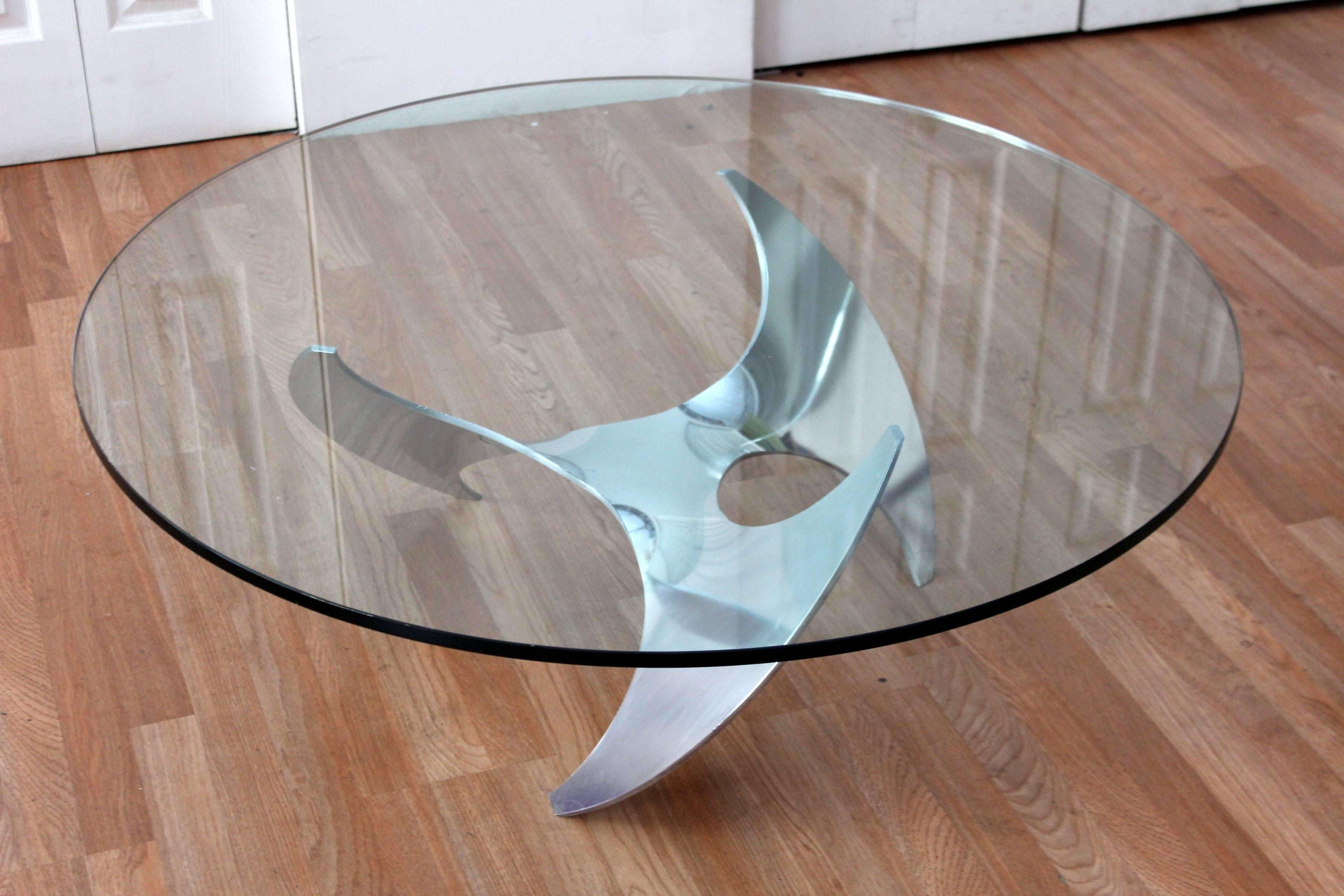 Coffee or cocktail table by Knut Hesterberg. The aluminum base sits in the form of a propeller and the top boasts a 2 inch thick glass top. This piece is perfect for adding a pop of interest to an otherwise heavy room.

Please remember to click