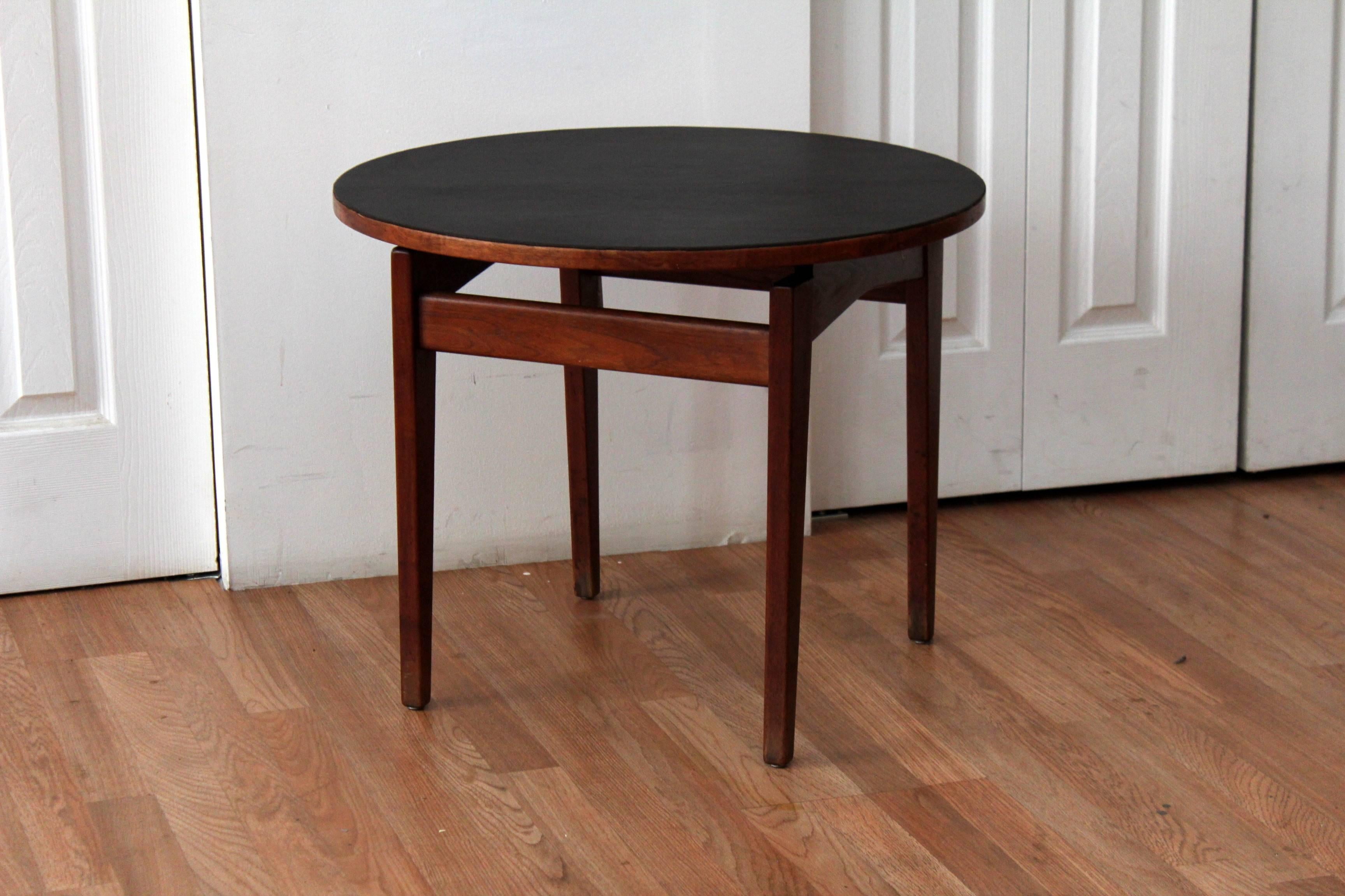 Jens Risom leather and walnut end or side table in solid walnut. The table boasts four tapered legs supporting a floating round walnut and leather covered top. One of the richest, prettiest patinas we've ever seen! Labeled.