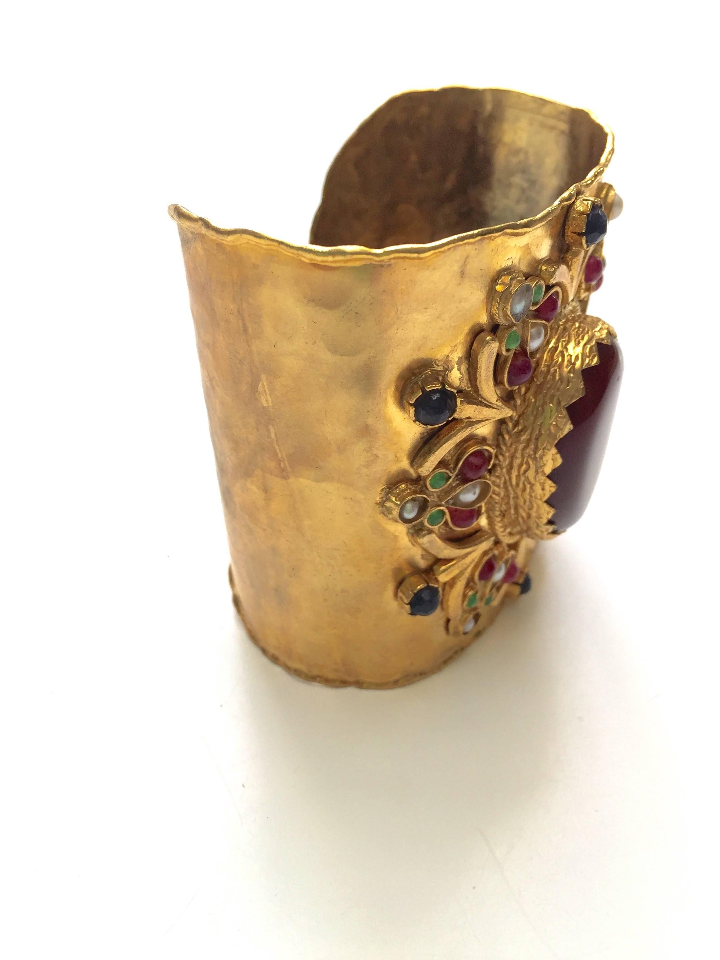 This gold plated cuff has a gorgeous brown agate centre stone, decorated then with little pearls and semi precious colored stones to create a beautiful pattern. It was made in Afghanistan by local craftsmen and makes a perfect accessory or the ideal