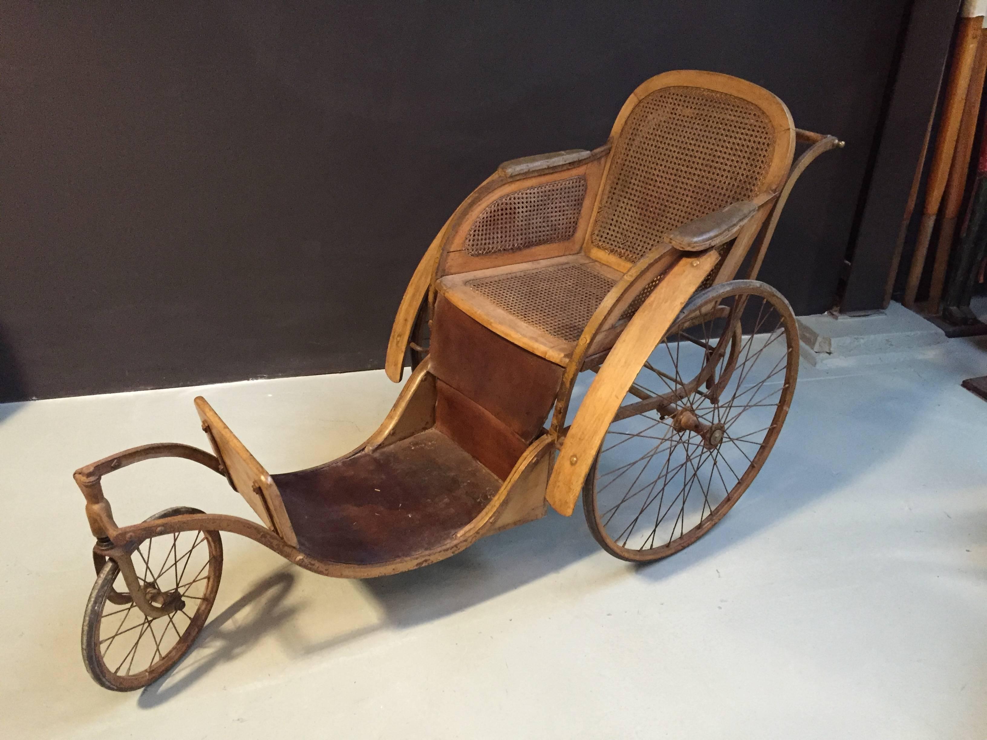 This vintage wheelchair was build in Paris in the 1920's. It has a rattan seat and a leather footboard.

