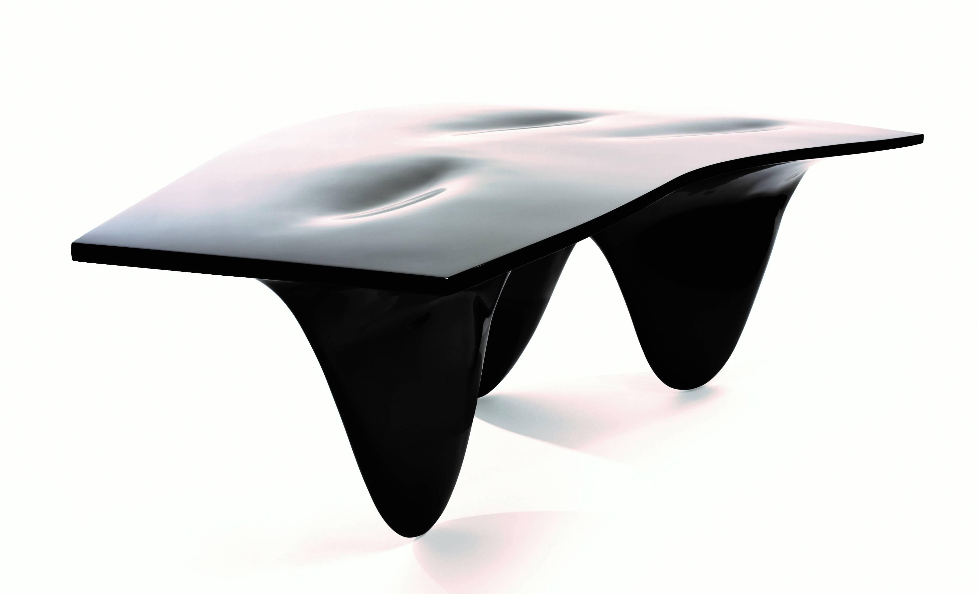 This Established & Sons Aqua table consists of three fin-like legs that appear to be in motion and register as gradients on the gently undulating tabletop. 
The Aqua table is an uninterrupted whole, a curious and curvaceous form that invites