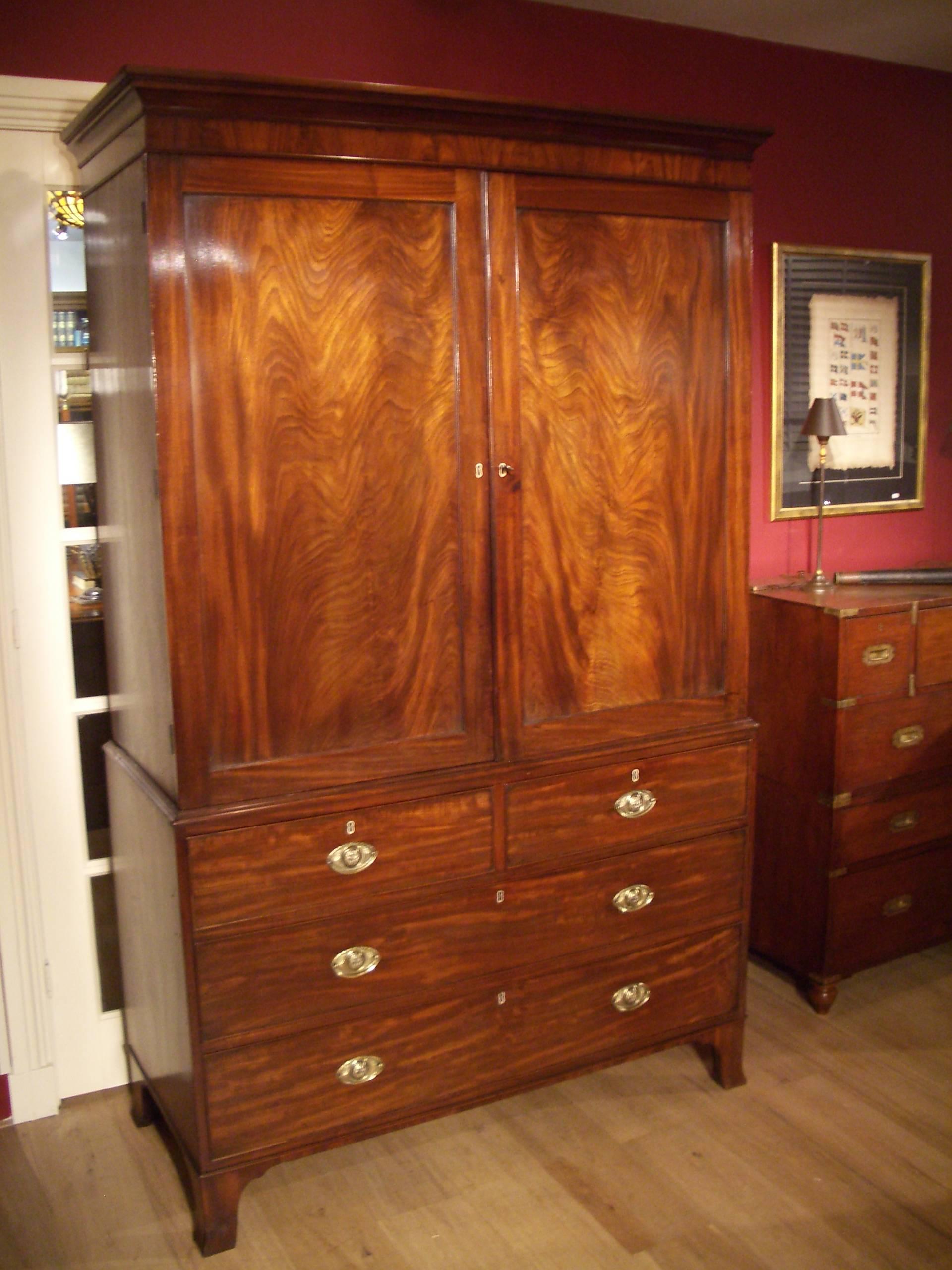 Beautiful English mahogany linen press in perfect and original condition. The mahogany door panels are particularly beautiful. Warm patina. Cockbeaded drawers fitted with brass handles, all standing on splayed feet The remarkable thing about the is