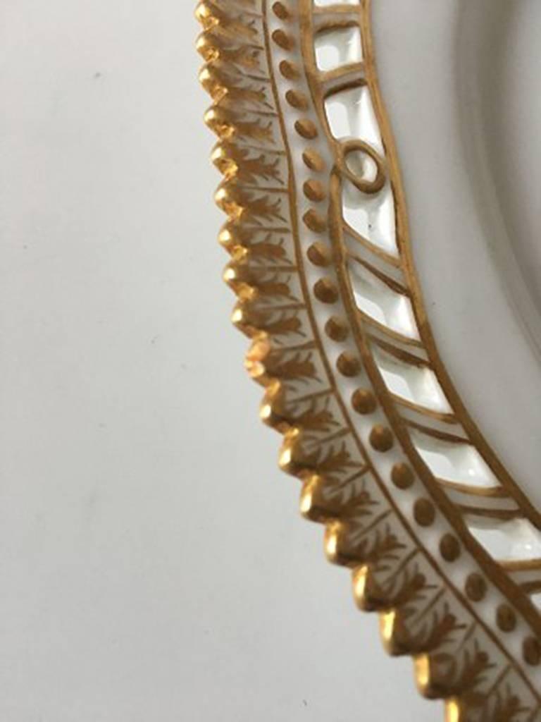 Royal Copenhagen Flora Danica Luncheon Plate with Pierced Border No. 20/3554. The plate has a small chip on the bord not easy to see at is has been repainted with gold. Measures 22.5 cm diameter (8 55/64 in).