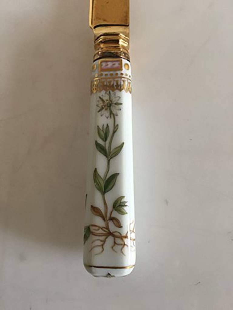 Royal Copenhagen Flora Danica Dessert knife 20 cm L ( 7 7/8 in). In porcelain with top in gilded sterling silver made by Anton Michelsen. The knife has a small hairline (look to picture for detail).
  