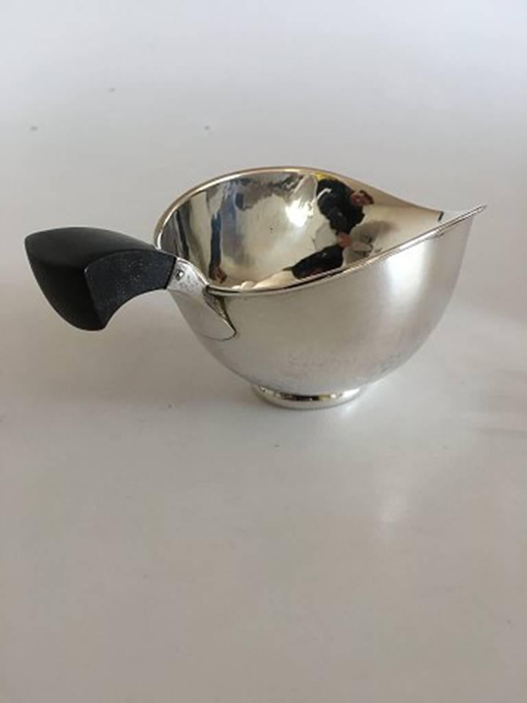 Aage Weimar small sauce pitcher in silver with wooden handle. Measures: 7 cm H. 11.5 cm diameter. Weighs 191 grams. In great condition.