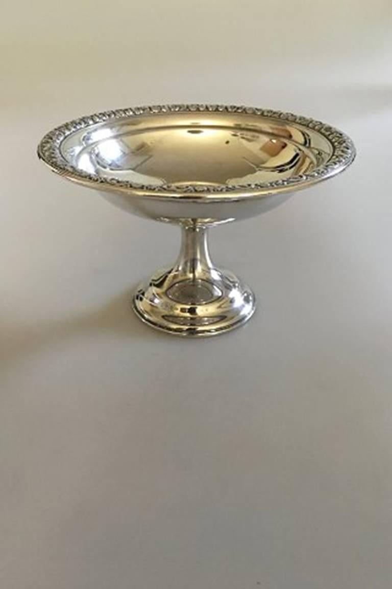 Wallace sterling silver footed bowl #168 with flower decoration on the round edge.

Measures 14.5 cm dia (5 45/64 in) and 9.5 cm H (3 47/64 in).