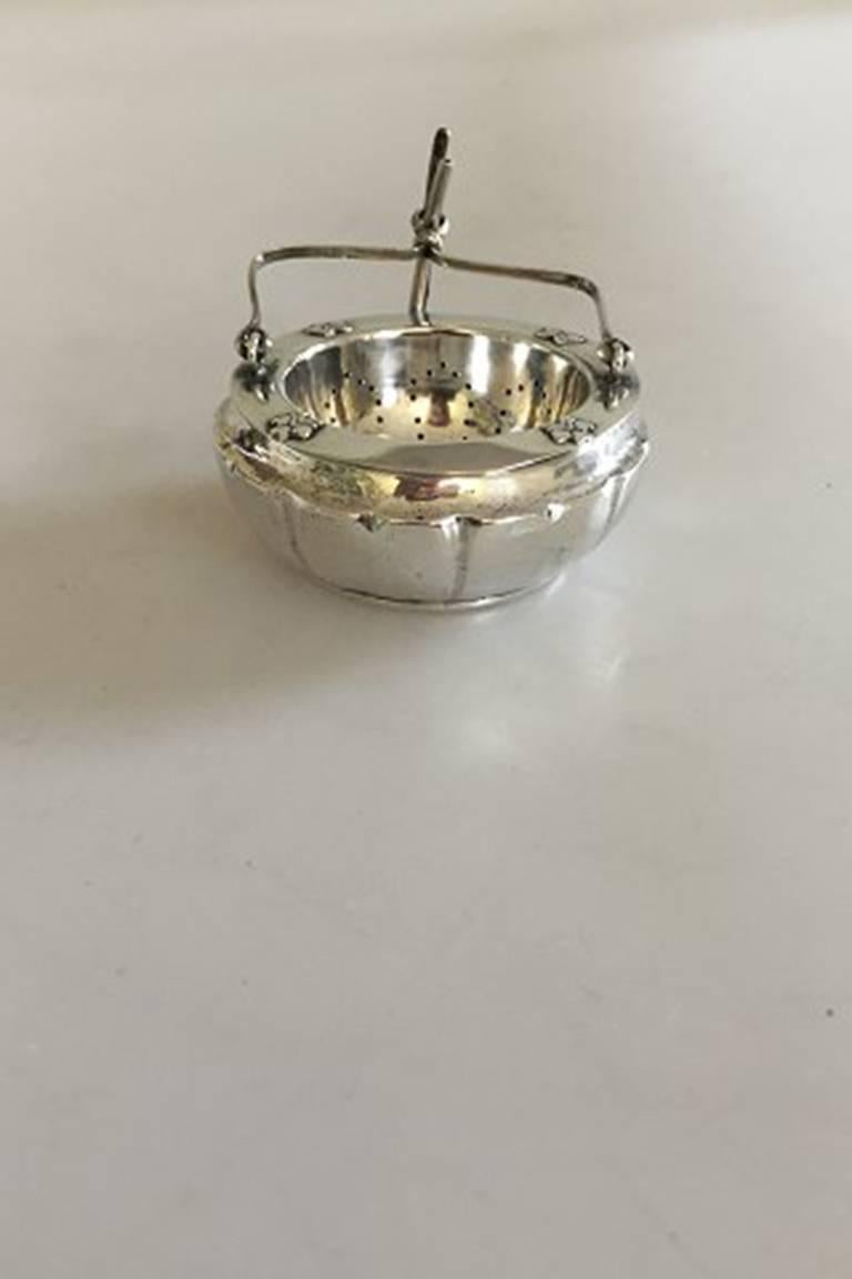 Danish tea strainer and holder in silver.

Weighs 65 g / 2.25 oz. Measures: 2.5 cm high (0 63/64 inches). 6.5 cm diameter (2 9/16 inches).