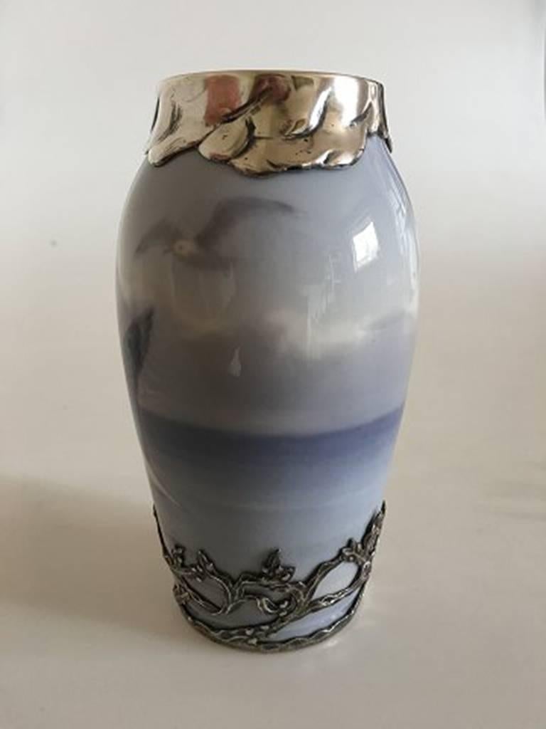 Royal Copenhagen Art Nouveau vase no. 1138/88A with seagull and sea motif. Anton Michelsen sterling silver top and bottom piece. 14 cm h. 1st quality. In nice whole condition.