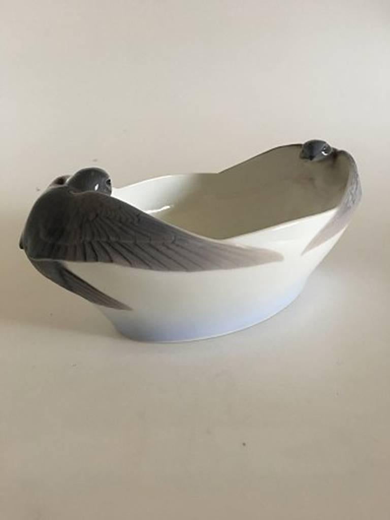 Royal Copenhagen bowl #674 in Art Nouveau style. Oval with two swallows. Measures: 31 cm. 12 cm H. 2nd quality in Nice and beautiful condition. One swallow has a few burning mistakes in the glazing.