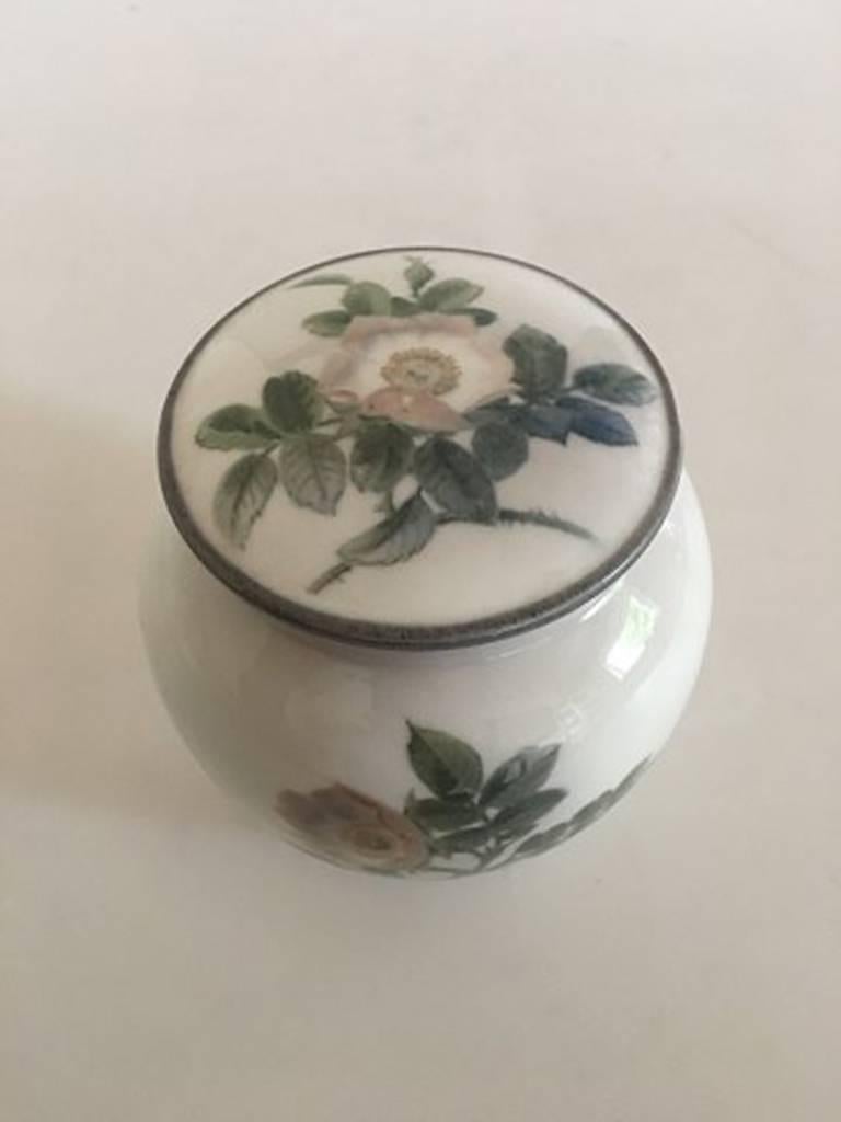 Bing & Grondahl lidded vase no. 367/445 with rose motif by Clara Nielsen. Measures: 11 cm H (4 21/64 inches). 1st quality from 1915-1947. In good condition.