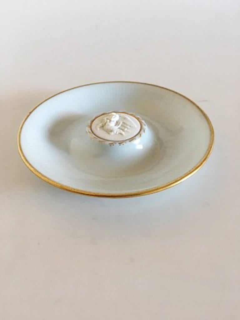 Bing & Grondahl ashtray no. 1291 with bisque angel ornament and gold border. Measures 12 cm diameter (4 23/32 in). In nice condition.