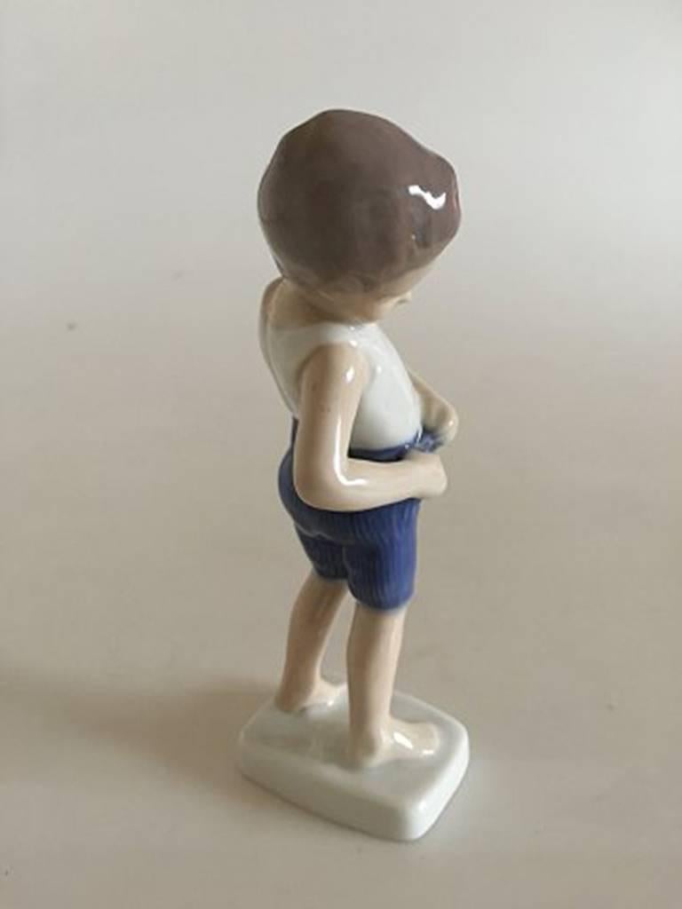 Bing & Grondahl figurine of boy looking in pocket #1759.

Measures 15cm / 5 9/10 in.